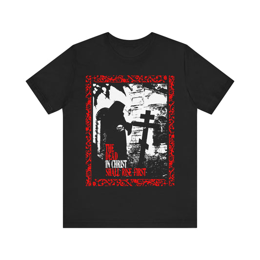 Black "The Dead in Christ Shall Rise First" T-shirt features a gothic graveyard design inspired by 1 Thessalonians 4:16, displaying a hooded figure by a cross. Orthodox Christian apparel. Color: Black.