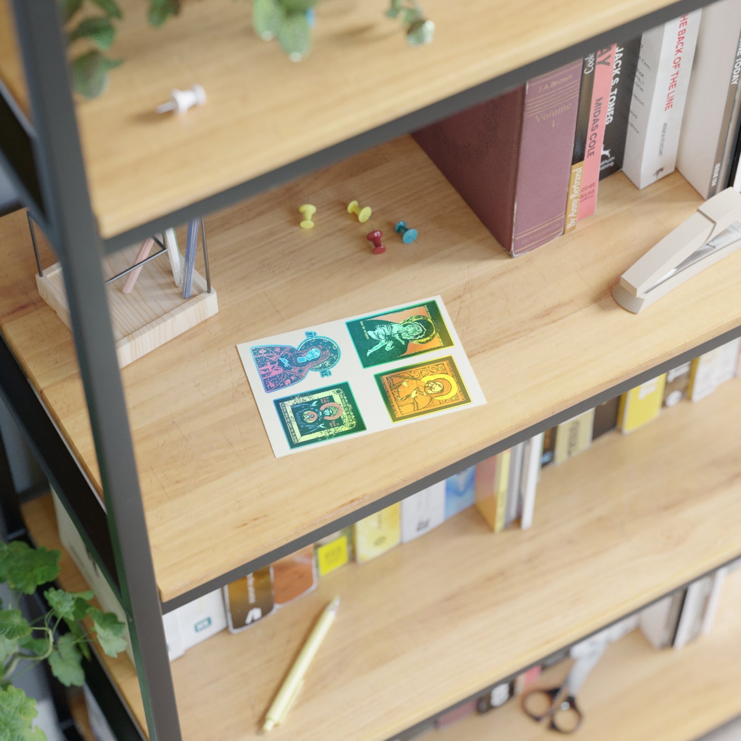 A wooden shelf with books, a stapler, push pins, a gold pen, and a postcard of four colorful animals. Remembrance of Death Theotokos IconoGraphic Sticker Collection No. 1 adds a touch of tradition. A small plant is partially visible on the left side.