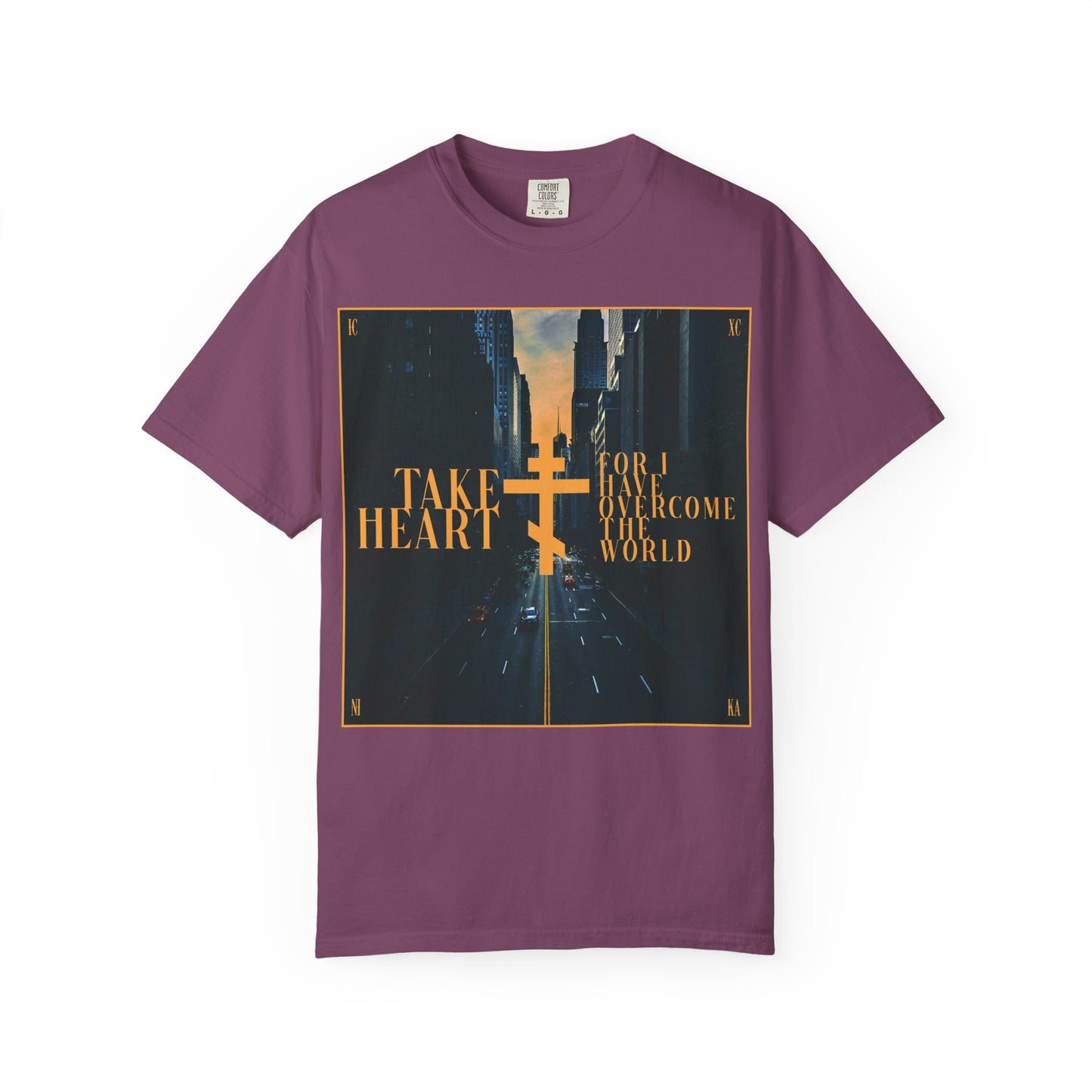 Berry tee featuring a redemptive modern city street scene with a gold cross and the text: “Take Heart, For I Have Overcome the World (John 16:33),” inspired by the promise of sorrow turning into joy.