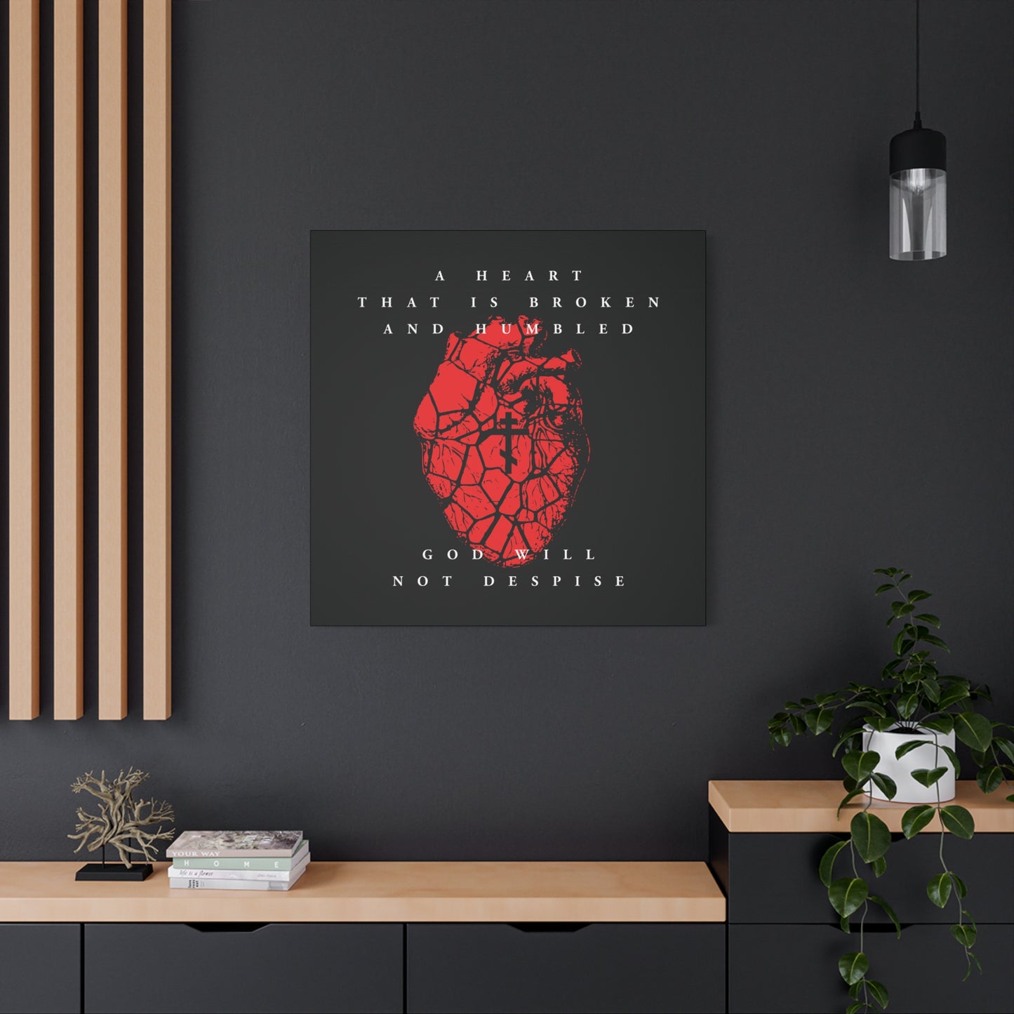 A Heart That is Broken and Humbled God Will Not Despise – a Christian canvas art print featuring a cracked red heart with an Orthodox cross, inspired by repentance, displayed on a dark wall above a plant and books.