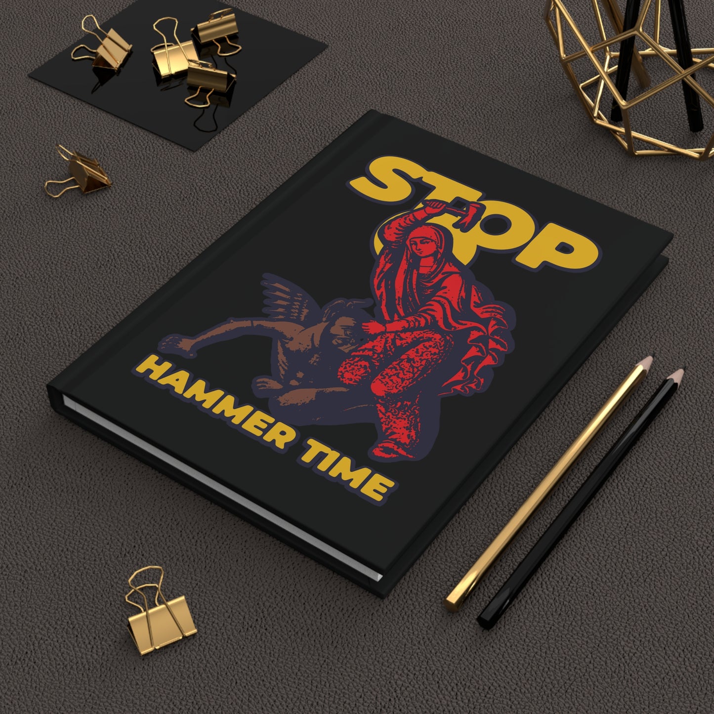 The "St Marina of Antioch Beating the Devil with a Hammer | Stop, Hammer Time" journal features red, blue, and yellow art inspired by Orthodox saints and Christian martyr tales—a modern meme notebook.