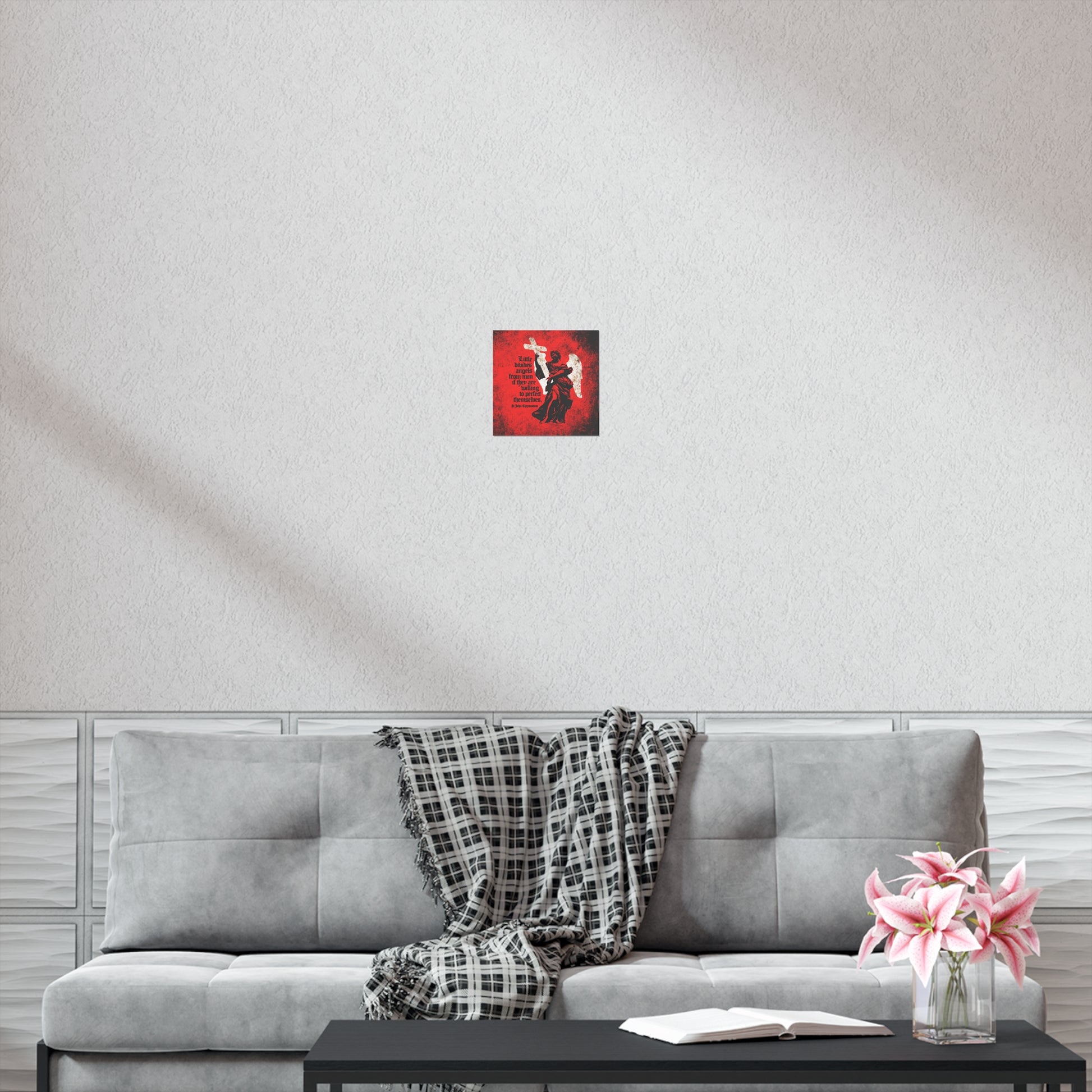 A gray sofa with a plaid throw, a book and flowers on a black table, and the "Little Divides Angels from Men" Christian Perfection art poster by St. John Chrysostom create a peaceful space for reflection.