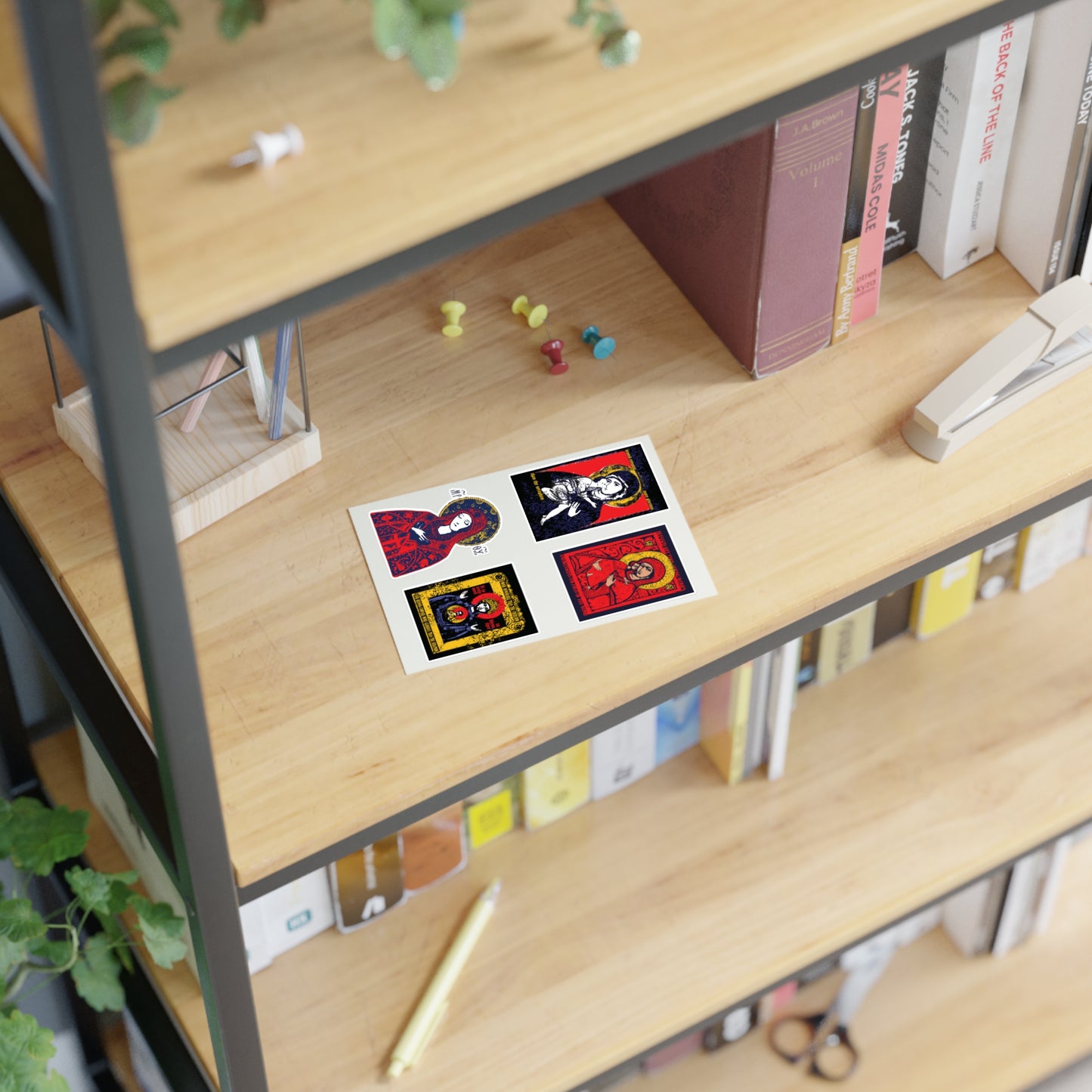 A wooden bookshelf holds books, plants, an hourglass, and push pins. On one shelf is a sheet from Remembrance of Death Theotokos IconoGraphic Sticker Collection No. 1, featuring colorful Orthodox Christian stickers, including a Vladimir “Of the Sign” icon.