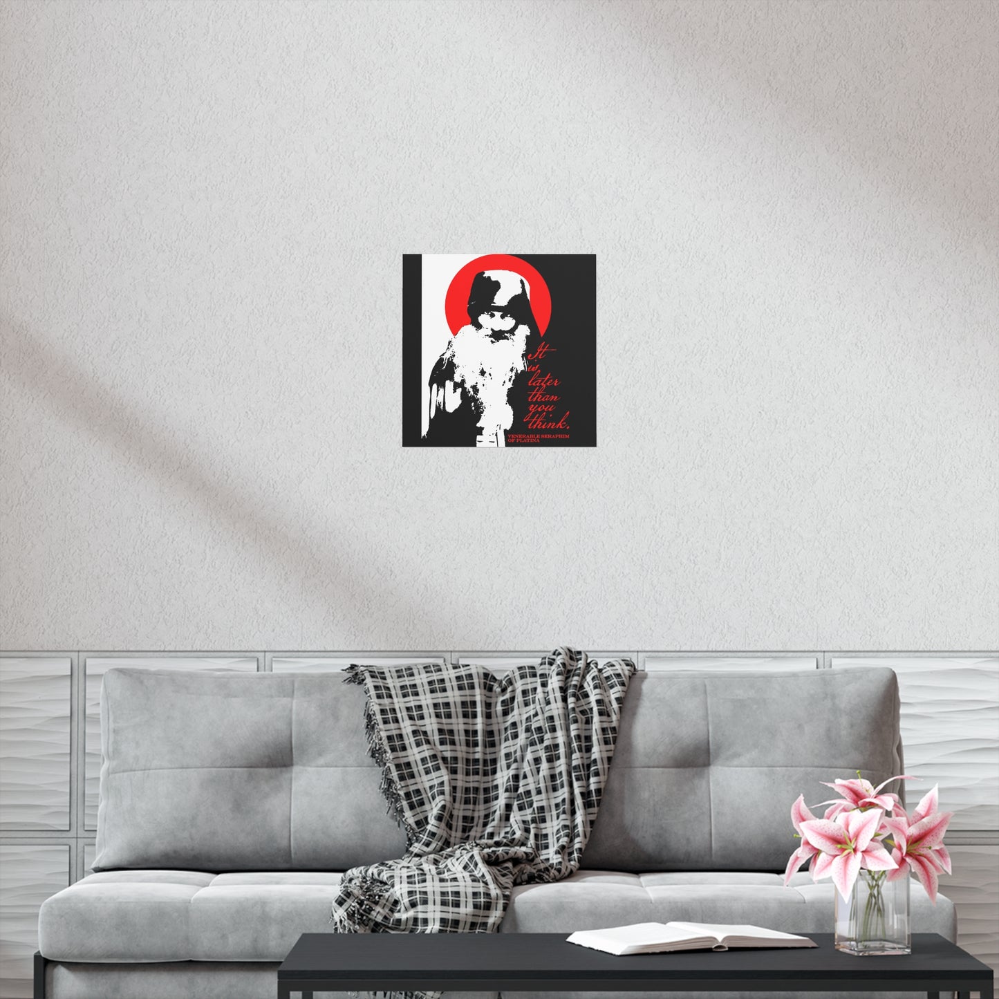A modern living room with a gray couch, plaid throw, and black coffee table, perfect for reading Orthodox texts, features Remembrance of Death "It's Later Than You Think | Fr Seraphim Rose" black, white, and red Christian art poster on the wall.