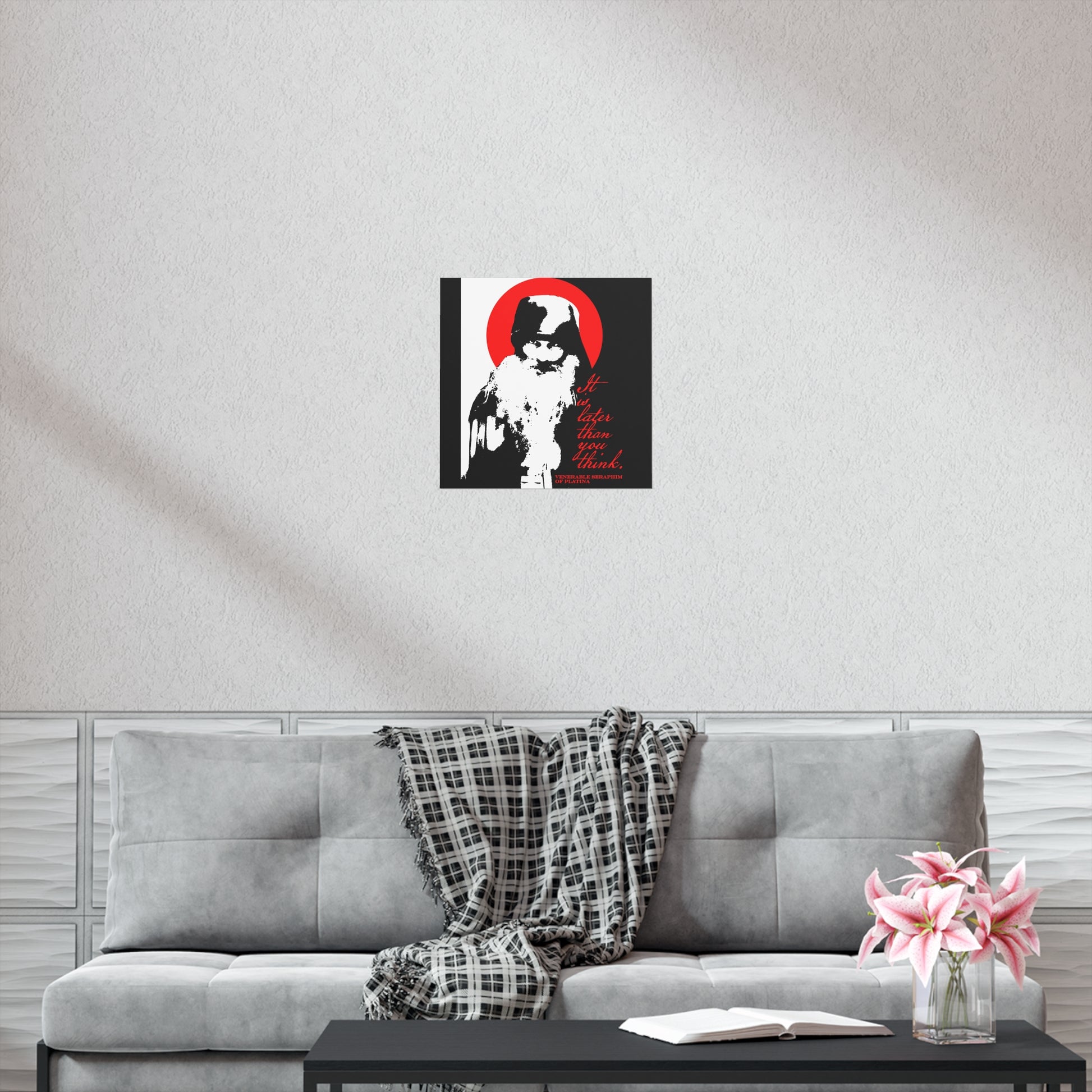 A modern living room with a gray couch, plaid throw, and black coffee table, perfect for reading Orthodox texts, features Remembrance of Death "It's Later Than You Think | Fr Seraphim Rose" black, white, and red Christian art poster on the wall.