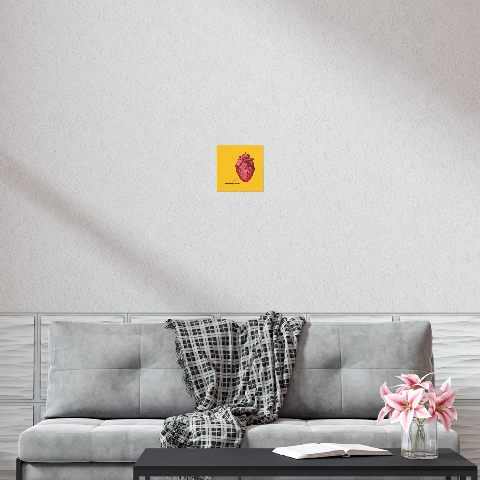 A gray sofa with a plaid throw, an open book on repentance, pink flowers, and a “Remember You Will Die” retro medical textbook heart Christian art poster with an Orthodox cross hang on the wall above.