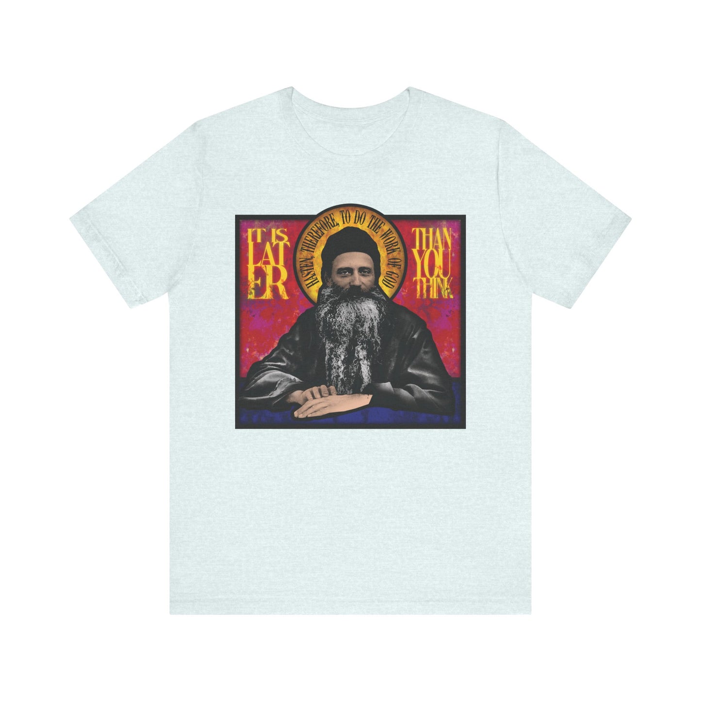 A Heather Ice Blue unisex T-shirt featuring a stained glass design of Fr. Seraphim Rose and the text “It is later than you think,” reminds us of salvation and honors this American Orthodox monastic saint.