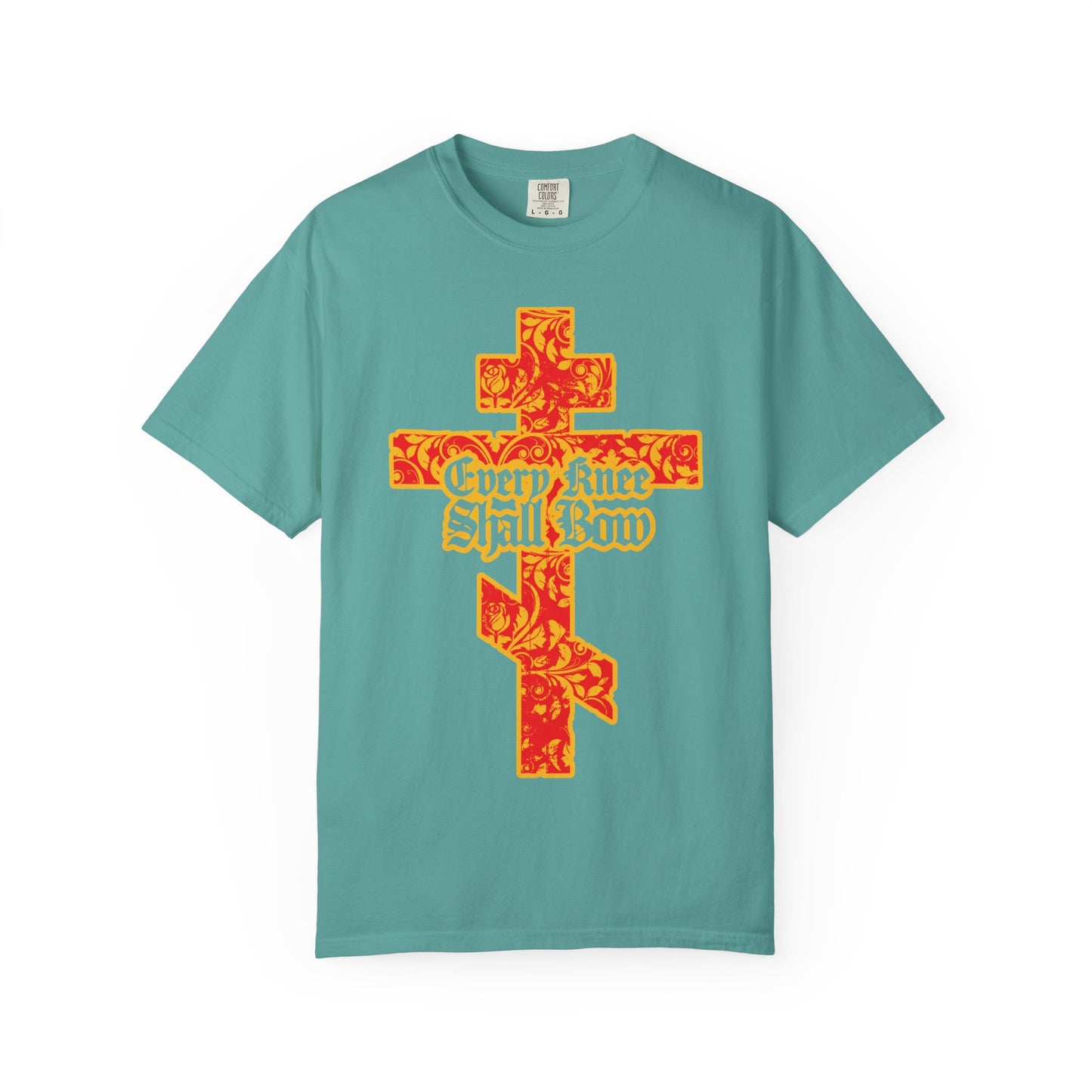 A seafoam heavyweight cotton unisex tee featuring a gold and red floral texture Orthodox cross and the phrase “Every Knee Shall Bow” in gothic letters on the front, inspired by Isaiah 45:22-24 and Philippians 2:7-11.