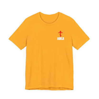 Gold t-shirt featuring a red Orthodox cross Christogram with bold white NIKA text, a NIKE logo mashup, and "Jesus Christ Conquers" message in a small design on the upper left chest.