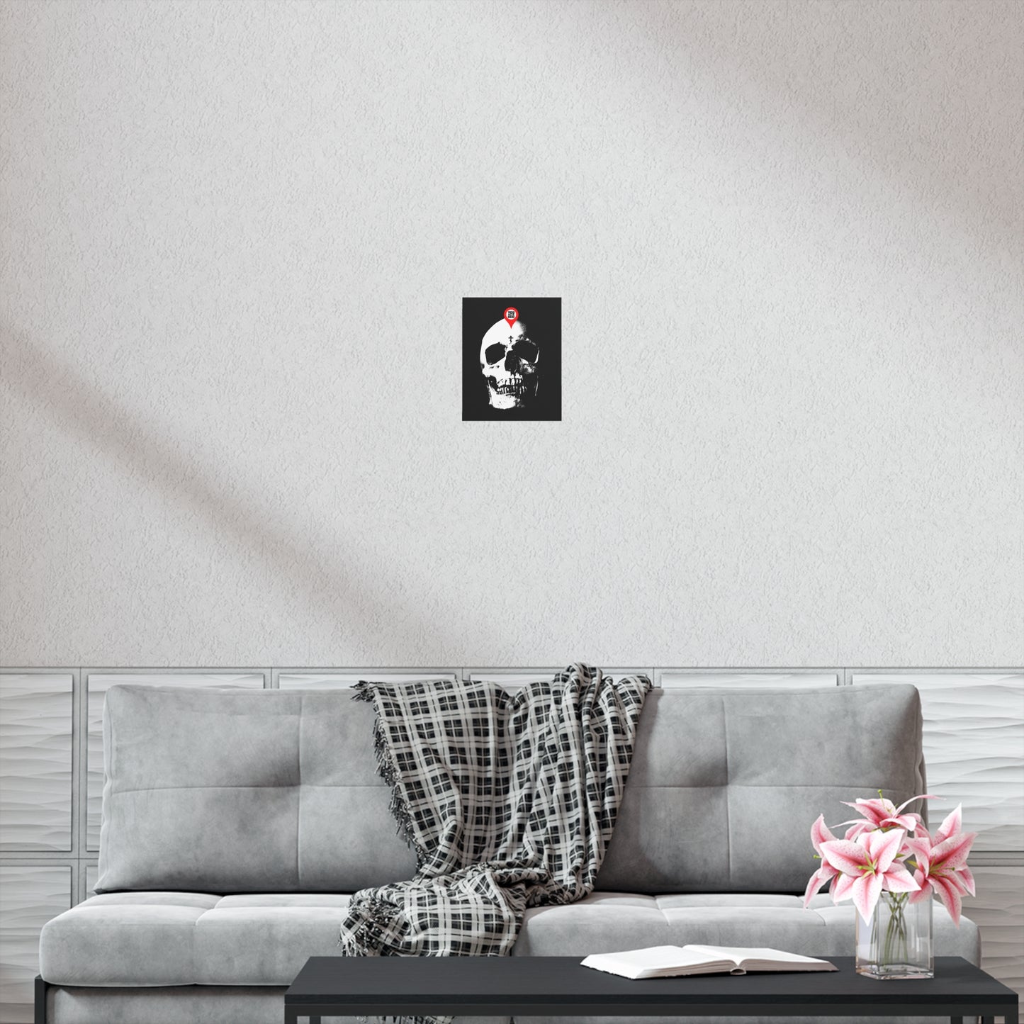 The "You Will Be Here Maps Marker on Skull" Memento Mori Orthodox Christian Art Poster hangs above a gray sofa with a plaid blanket, coffee table, and pink flowers, reminding viewers to reflect on the theme "remember you will die.