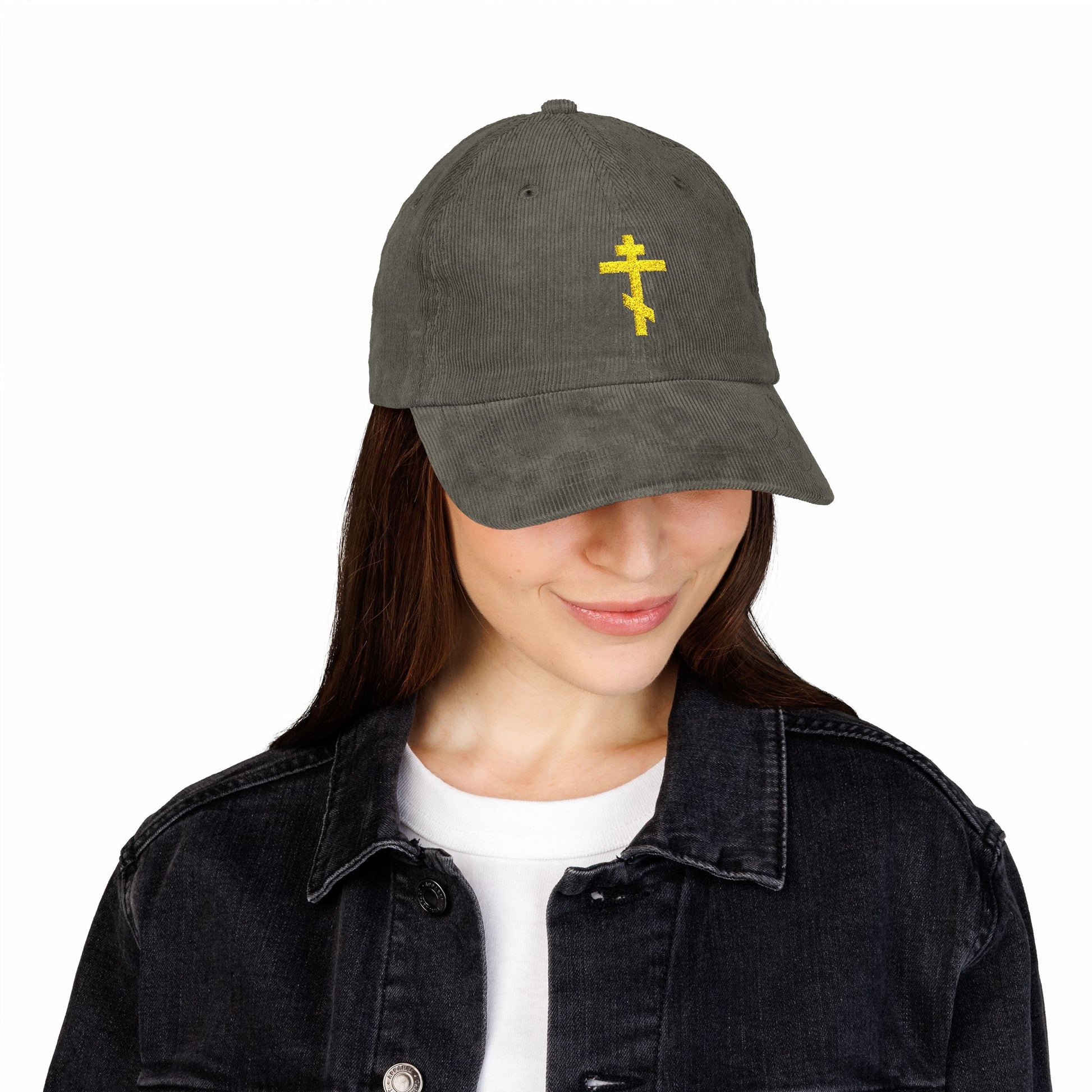 Woman wearing the Simple Yellow Orthodox TriBar Cross Embroidered Cotton Corduroy Cap—Weapon of Unseen Warfare Which Makes Demons Tremble—shows quiet reflection in her black denim jacket and white shirt.
