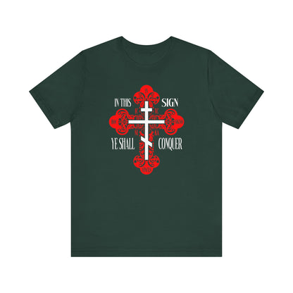 Forest green unisex tee featuring an ornate Orthodox cross with red accents, inspired by spiritual warfare. Text reads "In This Sign Ye Shall Conquer" in English and Greek (ICXC NIKA).