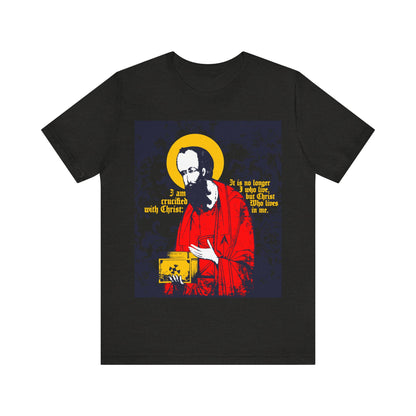 The Black Heather "St Paul Holding Gospel Iconographic" T-shirt features St. Paul with a yellow halo and the text "I am crucified with Christ—Galatians 2:20," expressing new life in Christ.