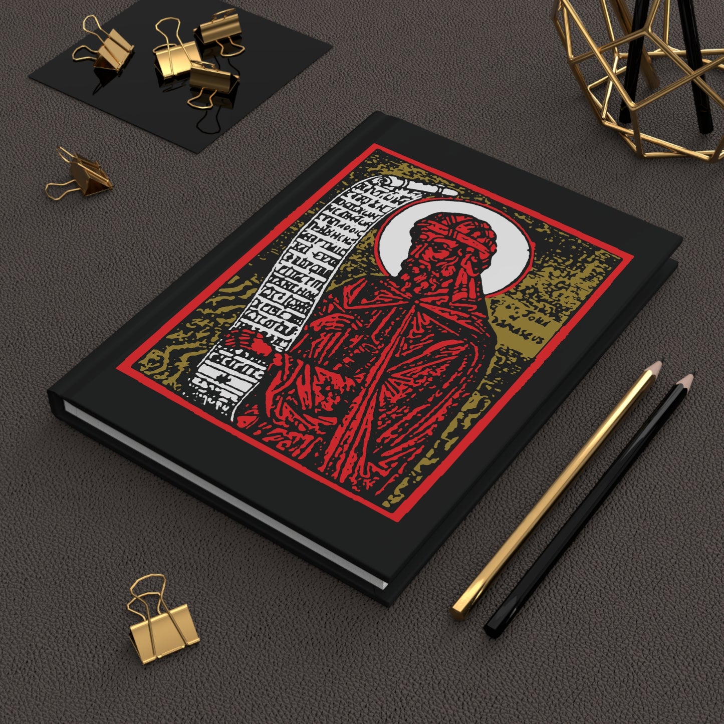 The "St. John of Damascus Icono-Graphic" hardcover journal features a bold red, gold, and black design—perfect for jotting down Orthodox hymns or Stichera for the Dead alongside your favorite desk accessories.