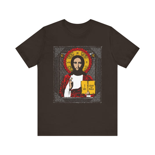 Brown tee with an icon-style illustration of Christ Pantocrator holding a book, featuring a red and gold halo. Inspired by "He-Who-Is" and "I Am the Alpha and Omega." Lightweight cotton unisex fit.