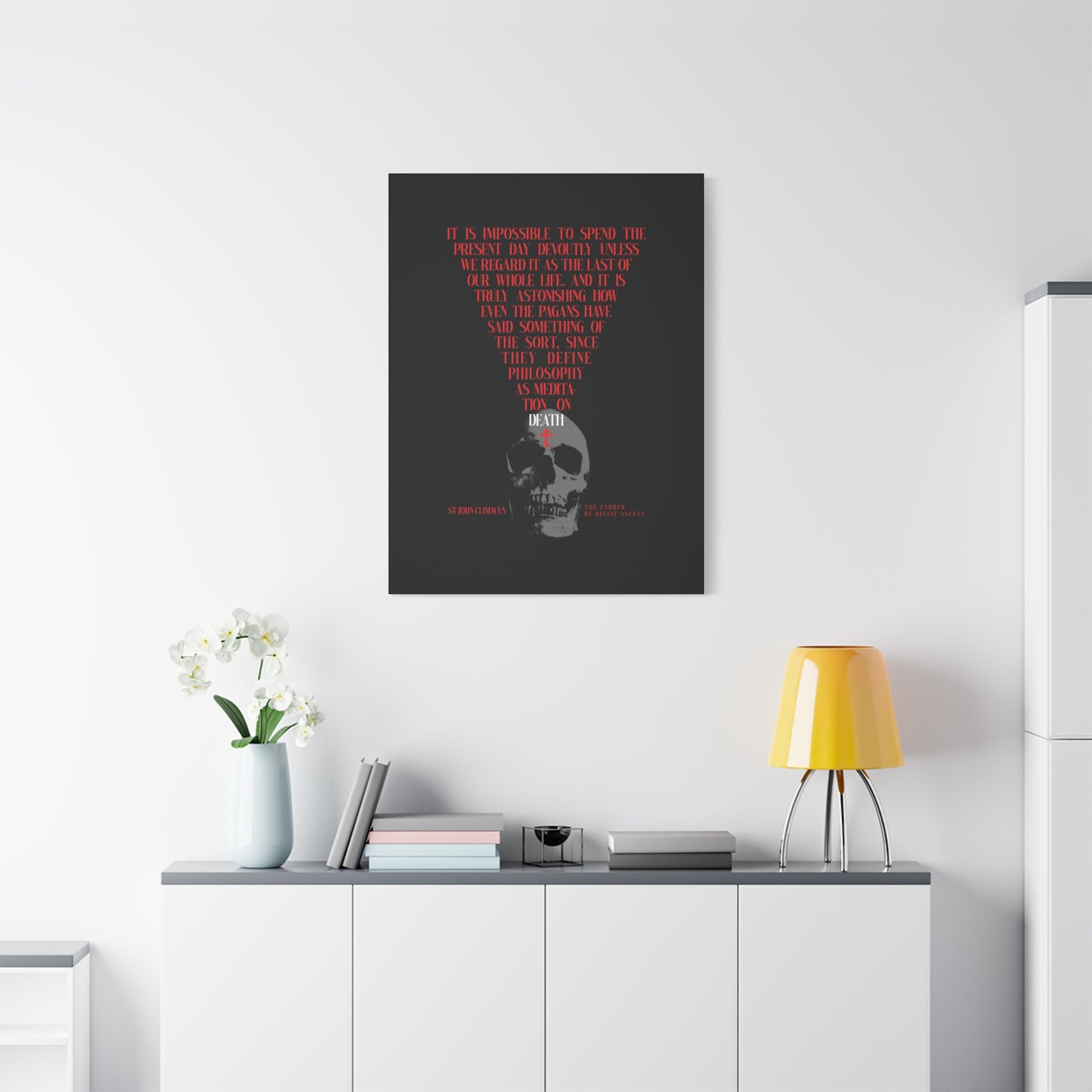 The "Present Day As the Last Day of Our Life" canvas, featuring a skull with a red Orthodox cross and memento mori theme, hangs above a white cabinet with plants and a yellow lamp.