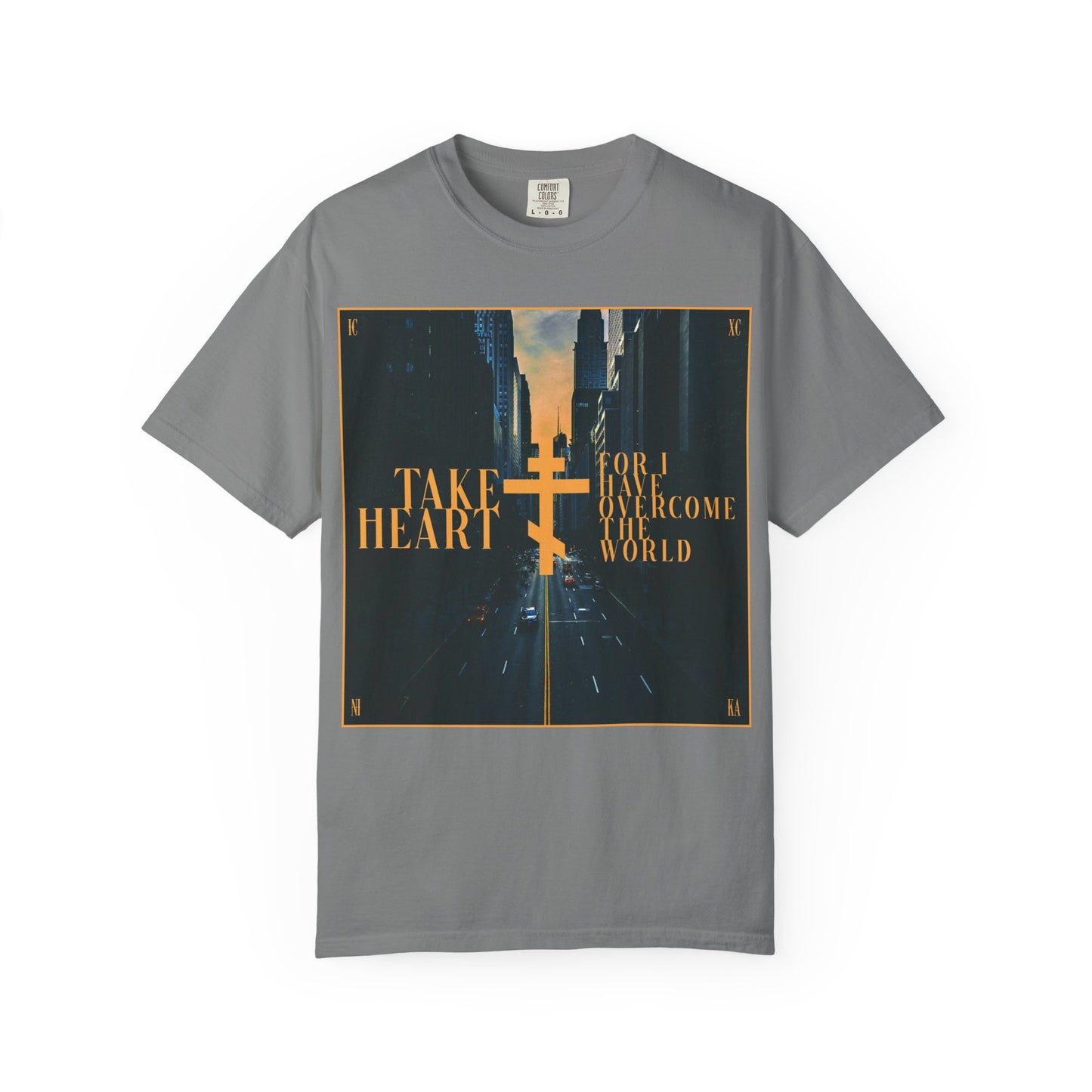 Introducing the "Take Heart, For I Have Overcome the World (John 16:33)" heavyweight cotton unisex tee in grey—featuring a modern city street scene at sunset, a gold cross accent, and inspiring text as a reminder that sorrow turns to joy when you ask and receive.