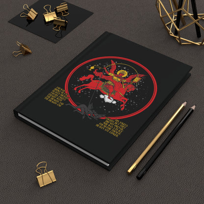A black notebook titled "Archangel Michael of the Apocalypse Icono-Graphic | War in Heaven (Rev 12:7-9) | Satan Cast Out | Orthodox Christian Journal" lies beside pencils and binder clips.