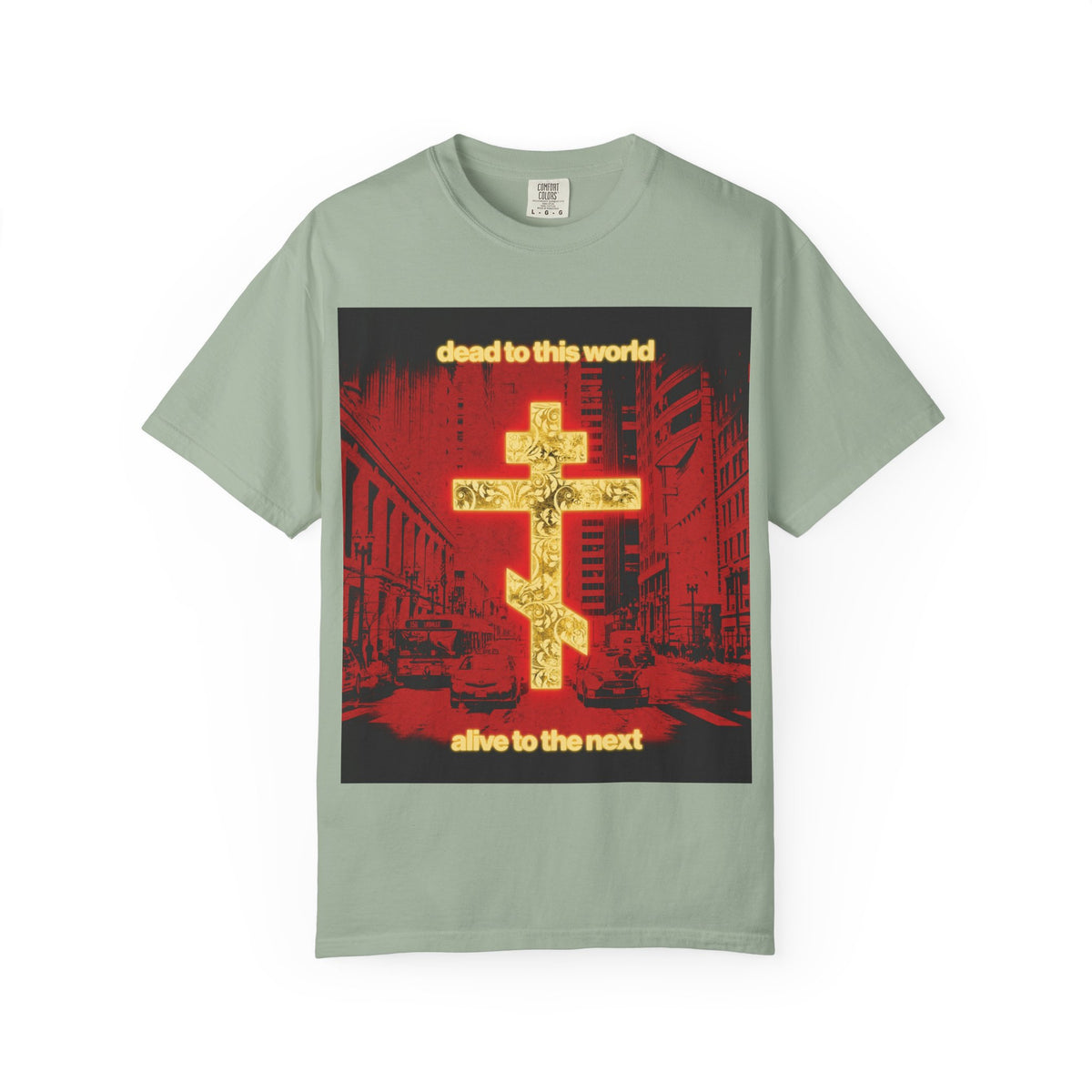 Bay-colored heavyweight cotton unisex tee, featuring a glowing gold cross over a red cityscape. The text reads “Dead to This World Alive to the Next,” offering an Orthodox Christian reflection on mortality and eternity.