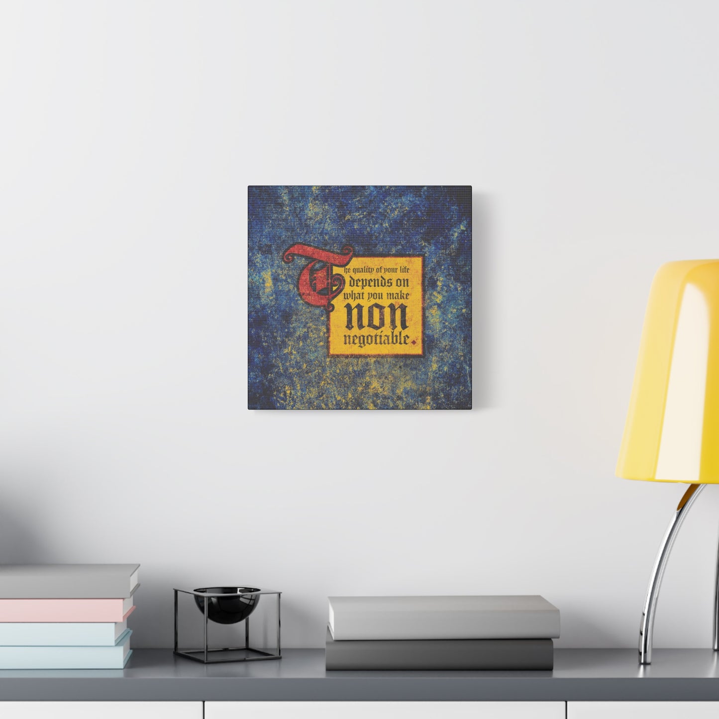 A square wall art titled "The Quality of Your Life Depends on What You Make Non-Negotiable | Uncompromising Christianity | Motivational | Christian Wall Art" hangs above a gray shelf with books and a yellow lamp.