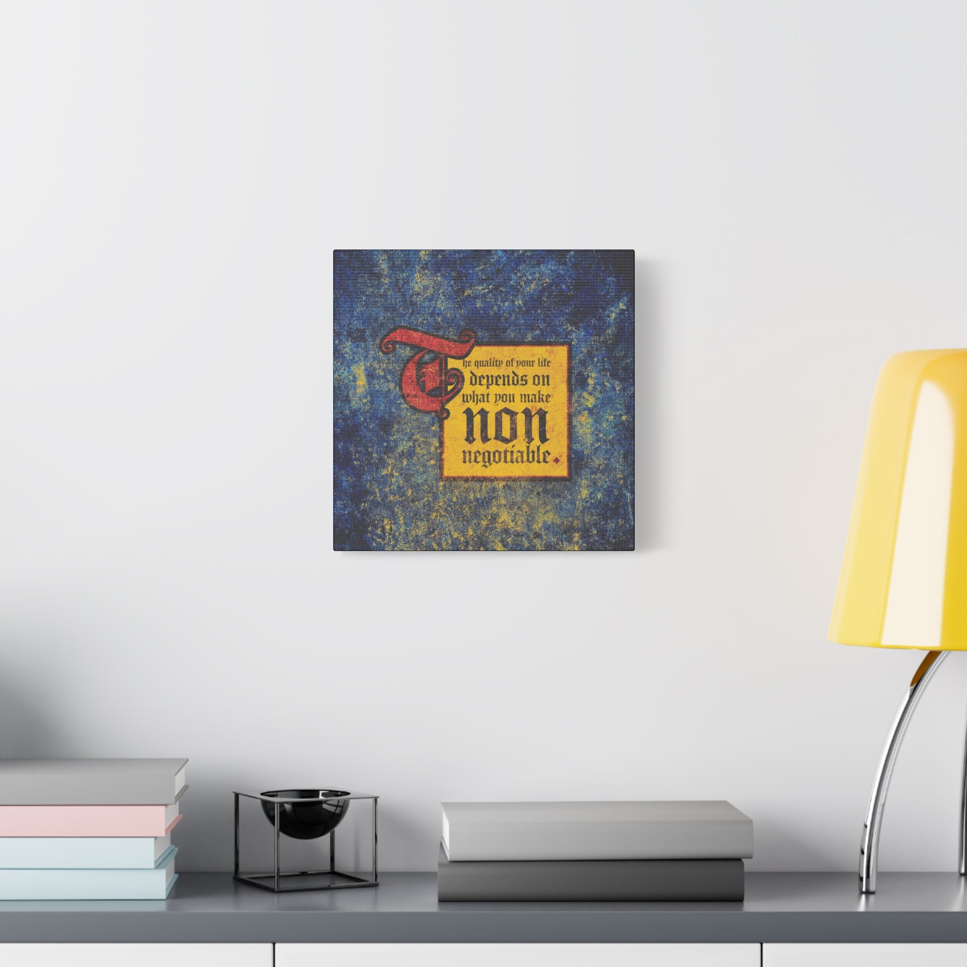A square wall art titled "The Quality of Your Life Depends on What You Make Non-Negotiable | Uncompromising Christianity | Motivational | Christian Wall Art" hangs above a gray shelf with books and a yellow lamp.