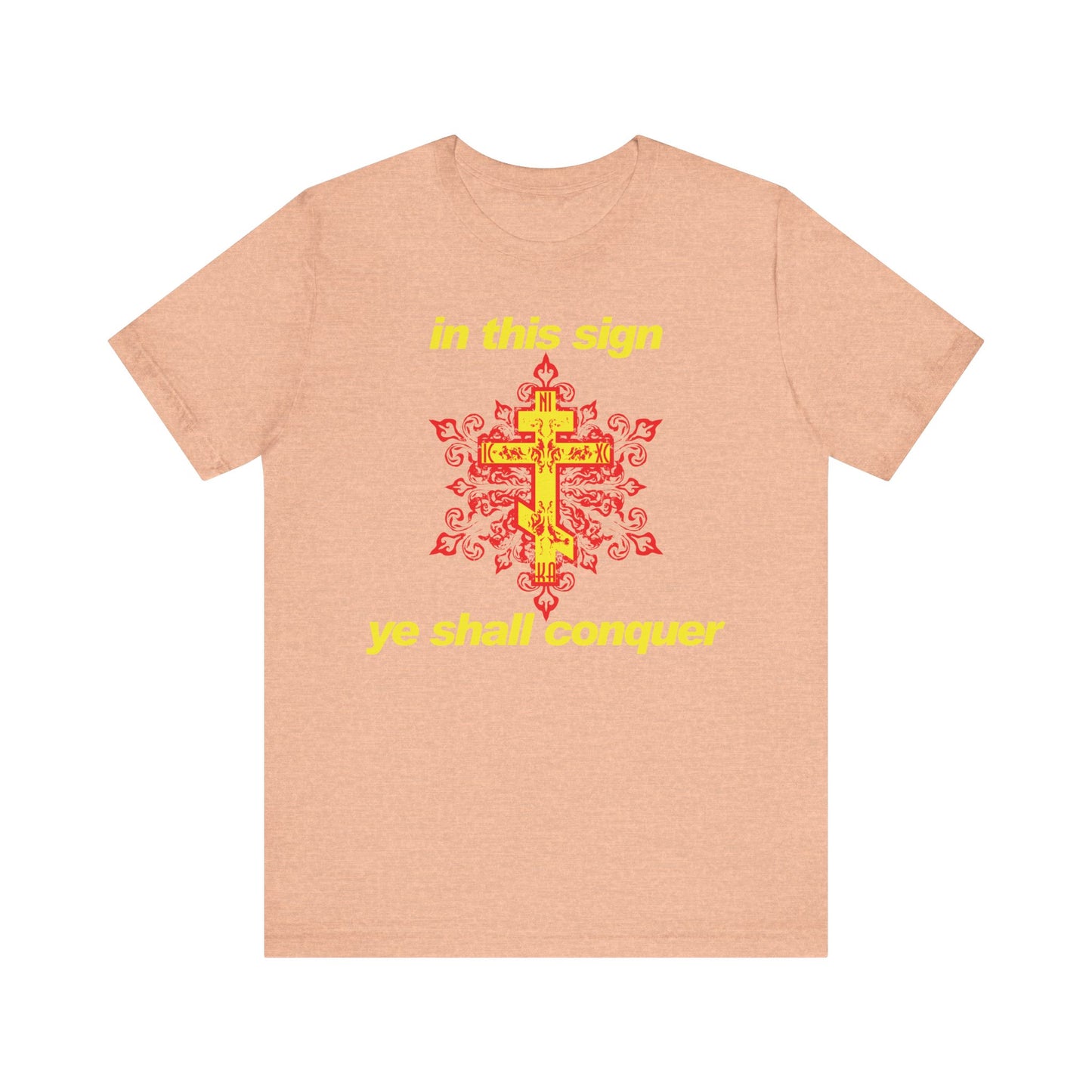 The "In This Sign Ye Shall Conquer" unisex t-shirt features modern red and yellow typography on a heather peach background, inspired by the spiritual teachings of St. Isaiah the Solitary. The phrase “in this sign ye shall conquer” is displayed in yellow, serving as both a prayer against temptation and a reminder of steadfast Orthodox Christian faith. Crafted from lightweight cotton for comfort, this shirt combines contemporary design with deep spiritual meaning.