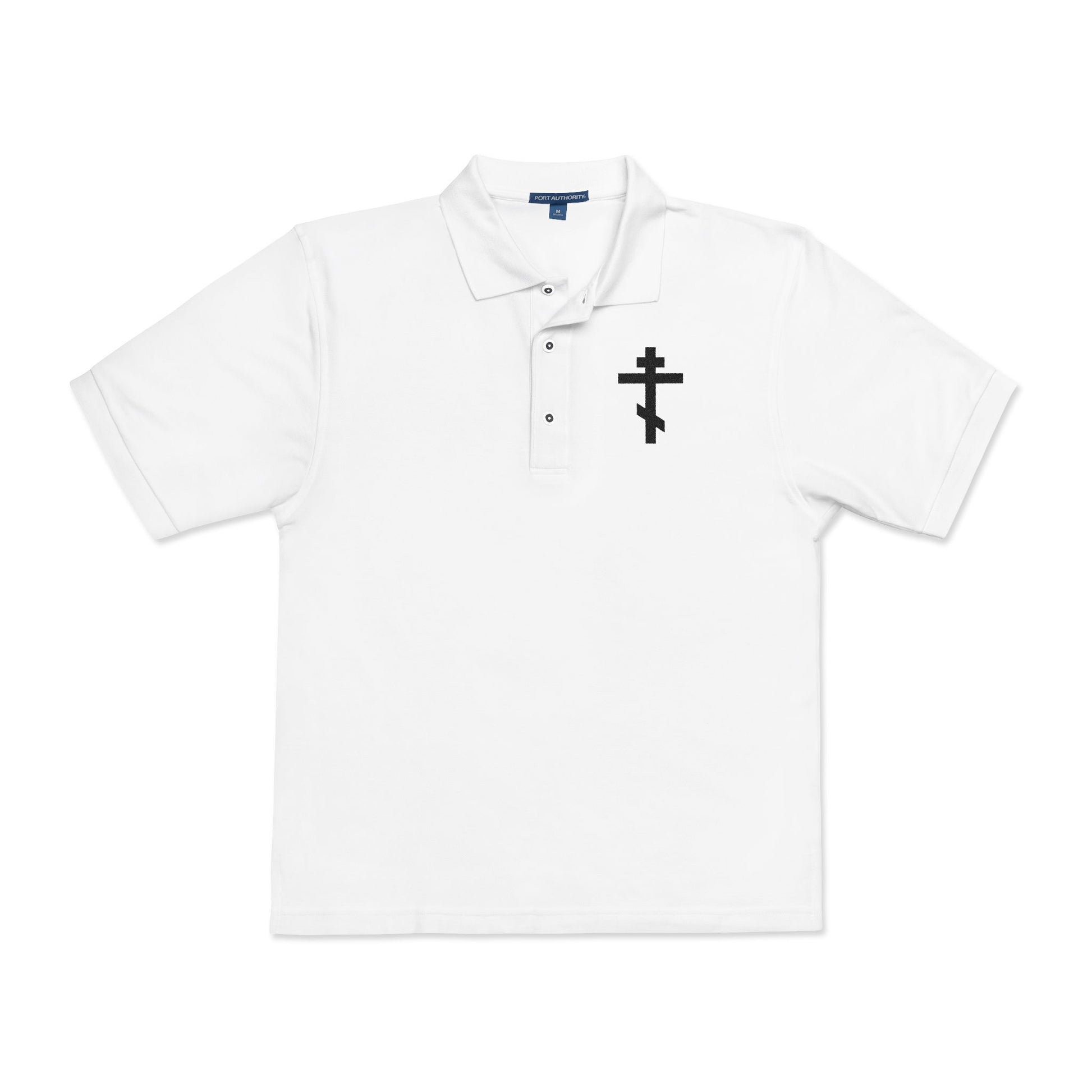 White polo shirt featuring an embroidered black Orthodox cross on the left chest, with the inscription "May I never boast, except in the cross of our Lord Jesus Christ" (Gal 6:14).