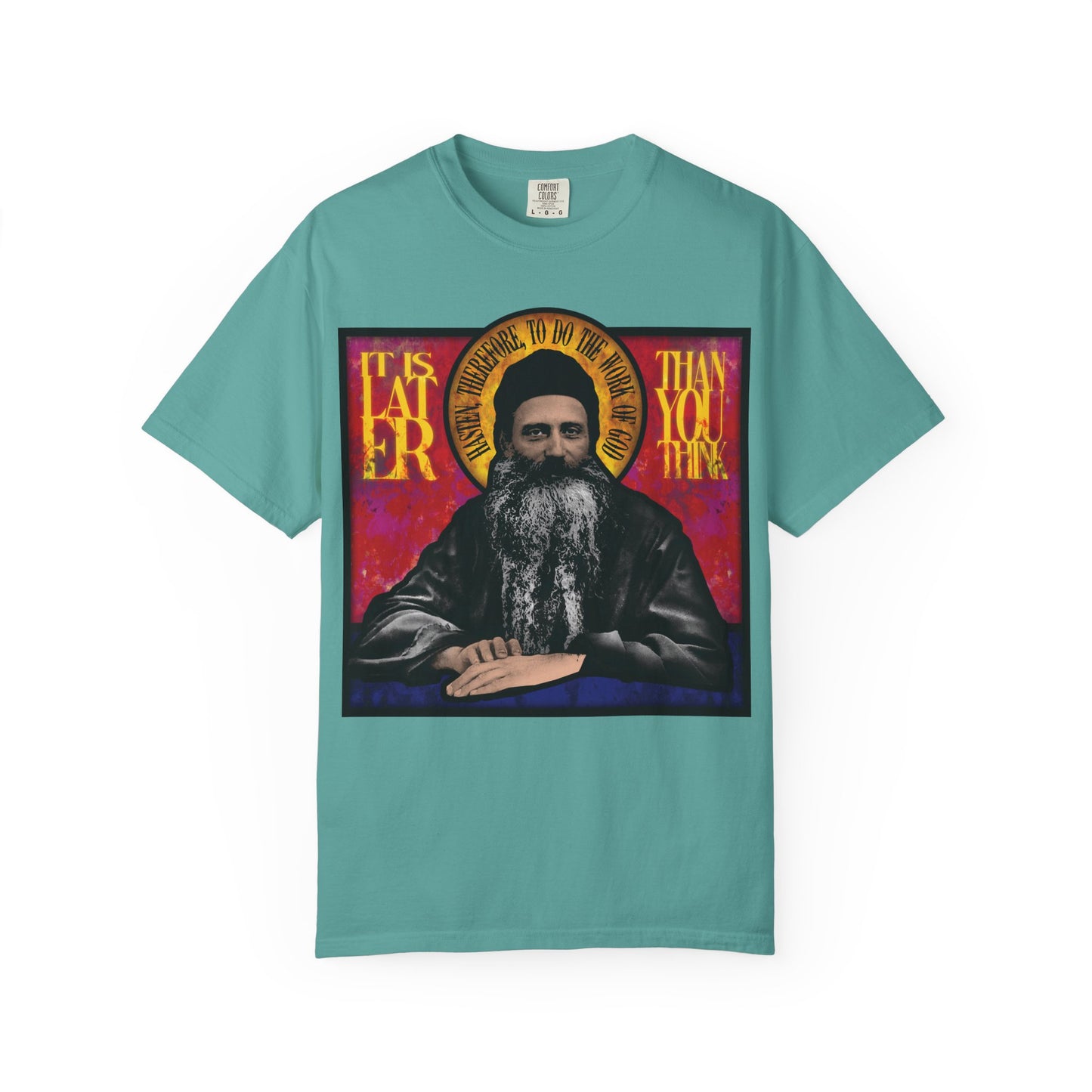 Teal heavyweight cotton unisex t-shirt featuring a stained glass design of Fr. Seraphim Rose with a halo and the text "It is later than you think"—a tribute to this American Orthodox monastic saint.