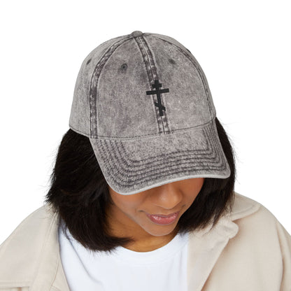 Person wearing the Simple Black Orthodox TriBar Cross cap, featuring a minimalist distressed design reading "Crucify My Ego to the Precious and Life Giving Cross," looking downward.
