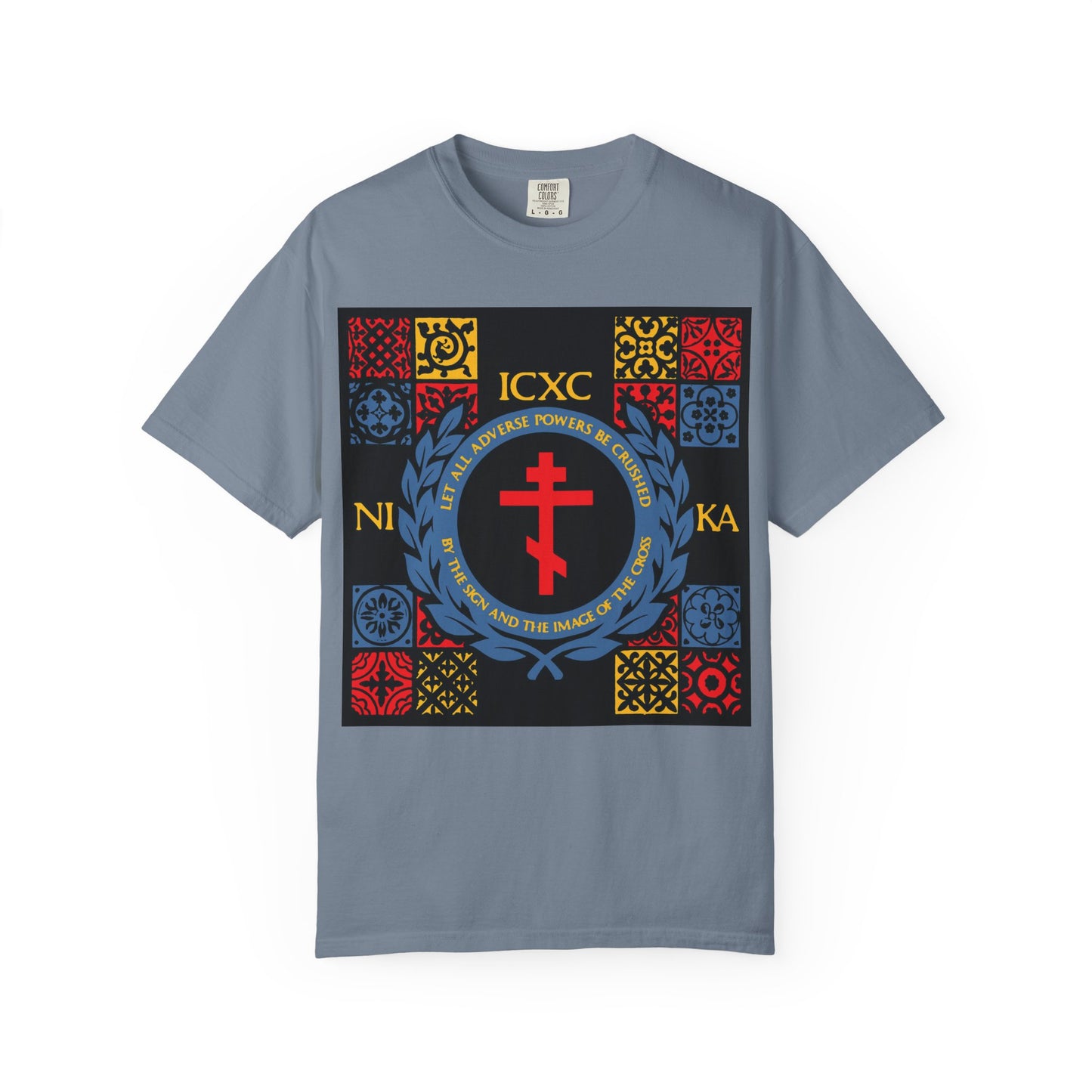 Blue Jean heavyweight cotton unisex T-shirt featuring a medieval tile-inspired design with Byzantine-style patterns, a prominent cross reminiscent of those in Katavasia hymns, a red cross, Greek ICXC NIKA lettering on the front, and accents in red, yellow, and blue. The product name is "Let All Adverse Powers Be Crushed.