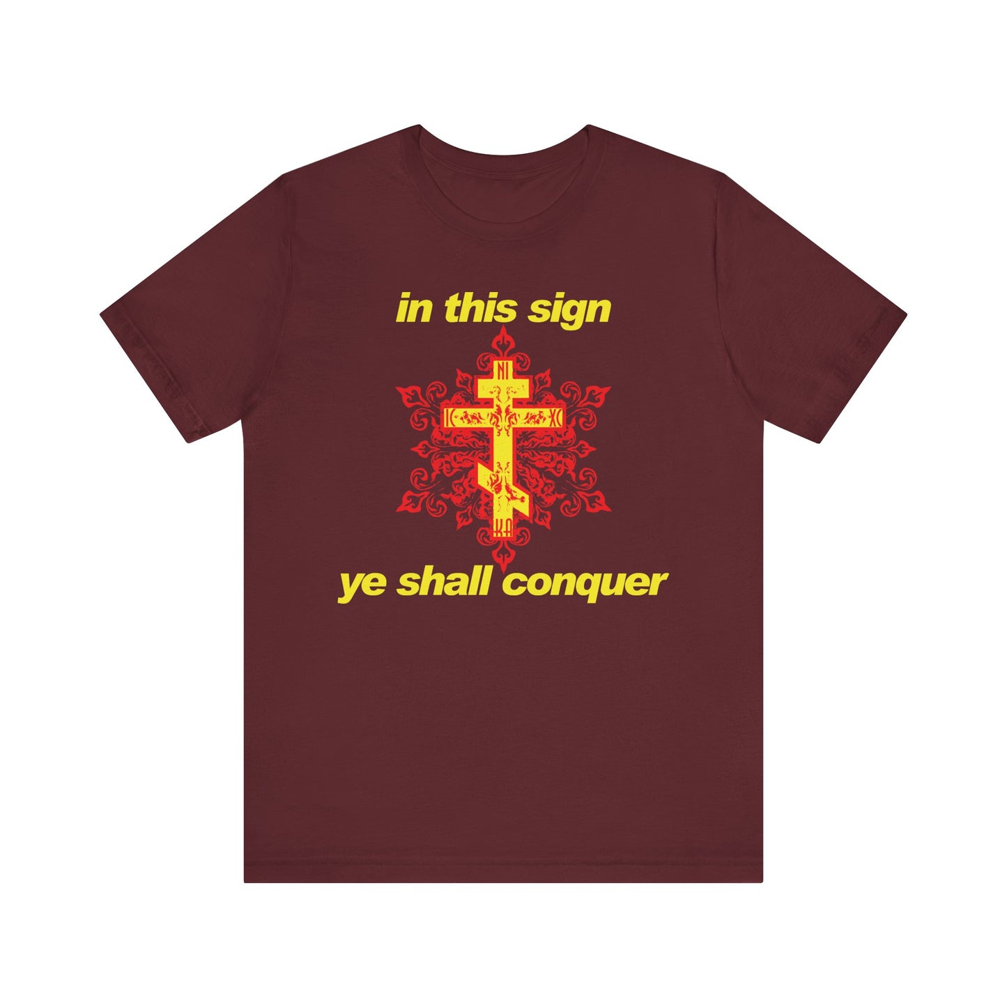 The In This Sign Ye Shall Conquer | Red and Yellow Design | Modern Typography | Orthodox Christian Lightweight Cotton Unisex T-Shirt features a maroon color with a gold cross, red accents, and yellow text that reads "in this sign ye shall conquer." Inspired by the wisdom of St. Theophan the Recluse, this shirt is a gentle reminder to seek strength through prayer against temptation in daily life.