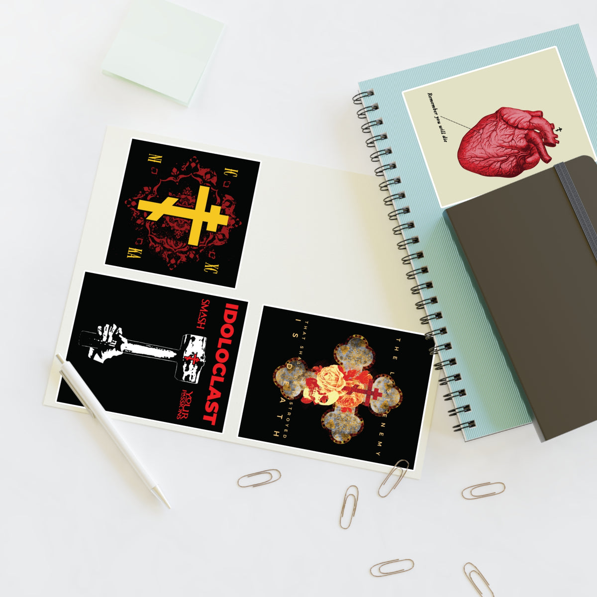 Open notebooks, a pencil, paperclips, and the Bestseller Mix No. 2 Four Orthodox Stickers on a white desk.