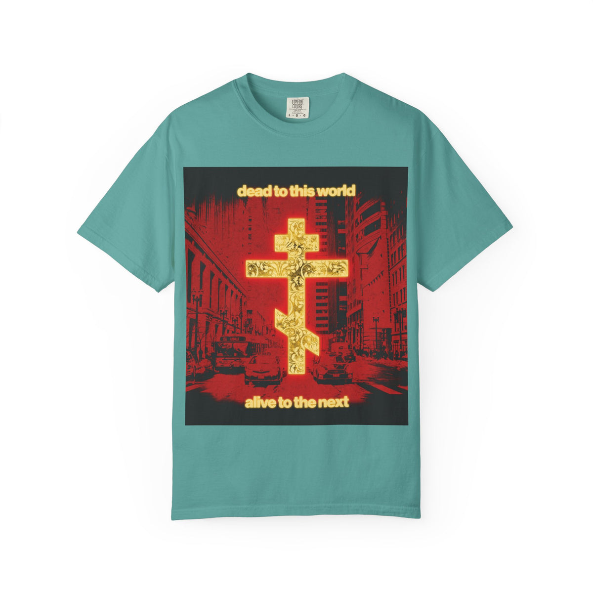 Seafoam heavyweight cotton unisex tee featuring a glowing gold cross, vibrant red cityscape background, and the phrase “Dead to This World, Alive to the Next”—a tribute to Orthodox Christian faith and the journey from death toward destiny.