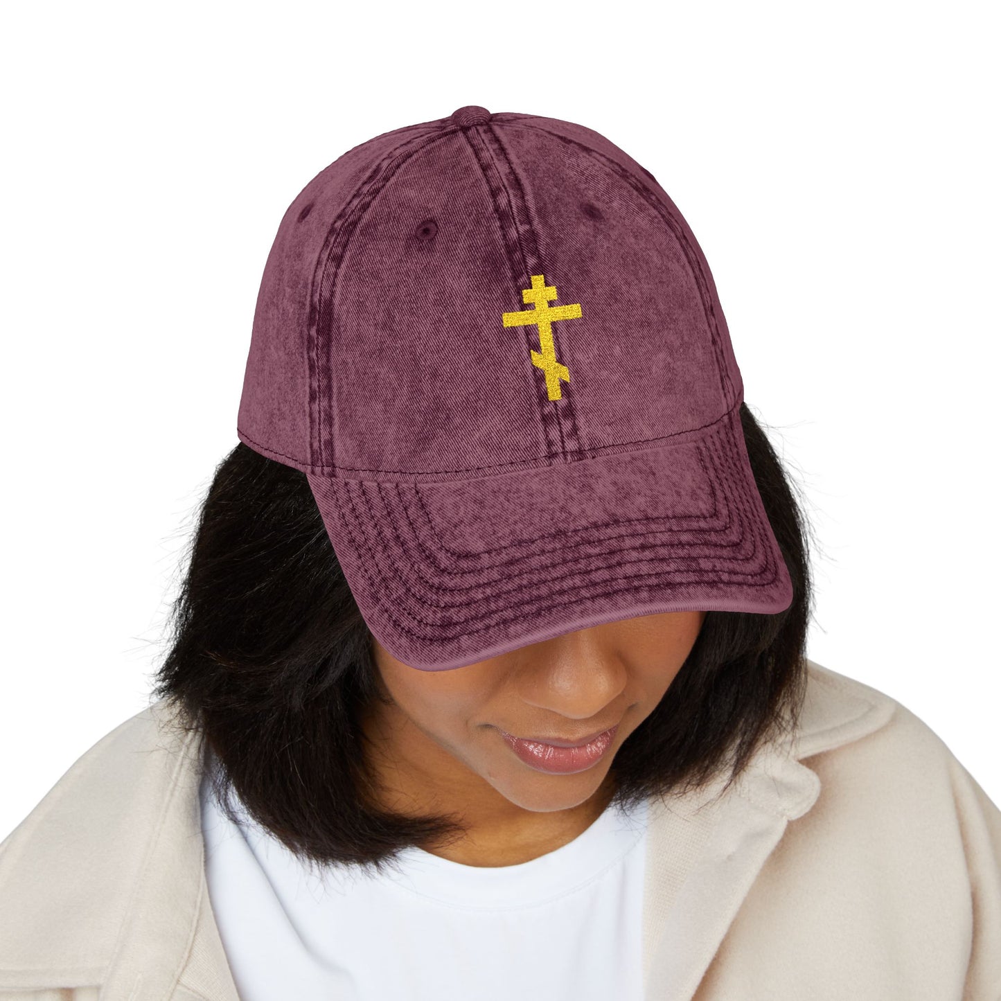 A woman wearing the Simple Yellow Orthodox TriBar Cross minimalist Christian cap, embroidered with "Crucify My Ego to the Precious and Life Giving Cross," looks downward in quiet reflection.