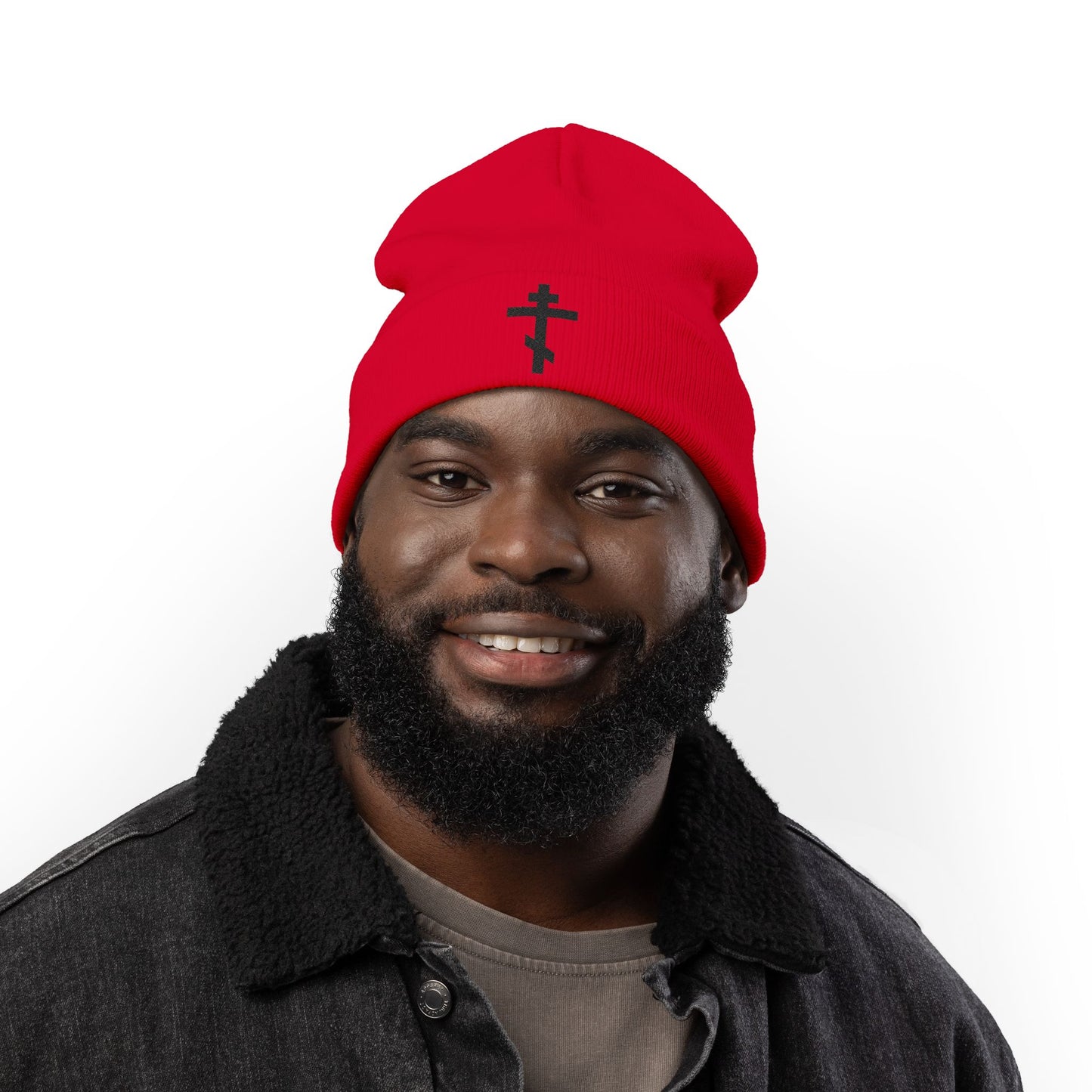Smiling man in a Simple Black Orthodox TriBar Cross beanie, embroidered with "Nail My Passions to the Wood of Thy Precious Cross O Lord," wearing a dark jacket against a white background.