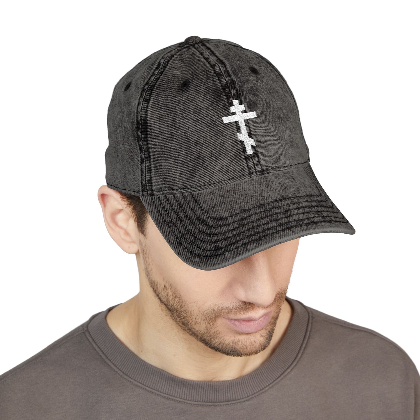 Man wearing the Simple White Orthodox TriBar Cross cap, a minimalist Christian distressed embroidered hat that reads "Crucify My Ego to the Precious and Life Giving Cross," quietly reflecting.