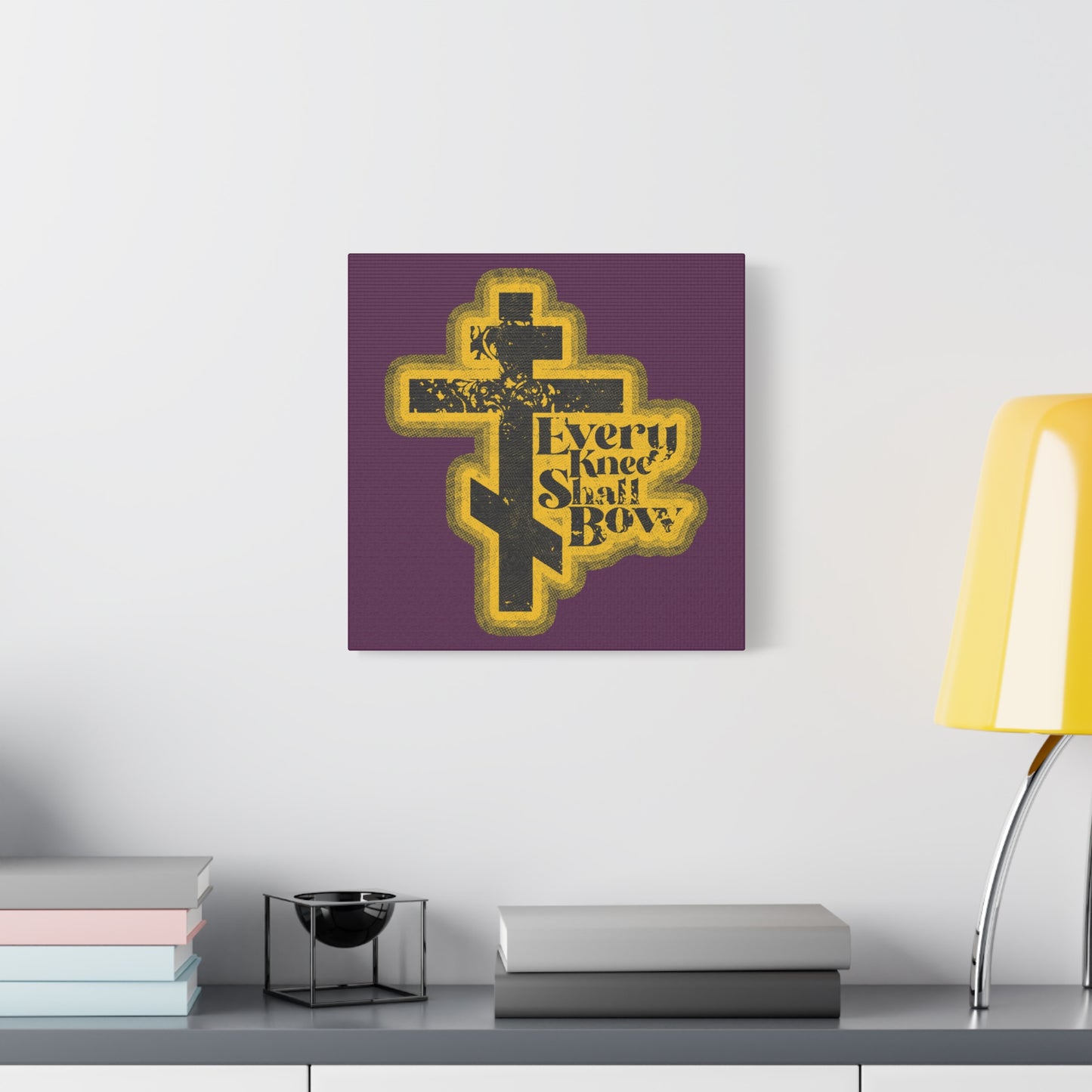 A 70s distressed halftone comic book style wall art, "Every Knee Shall Bow," featuring Philippians 2:10-11 and Isaiah 45:23, displayed above a modern desk.