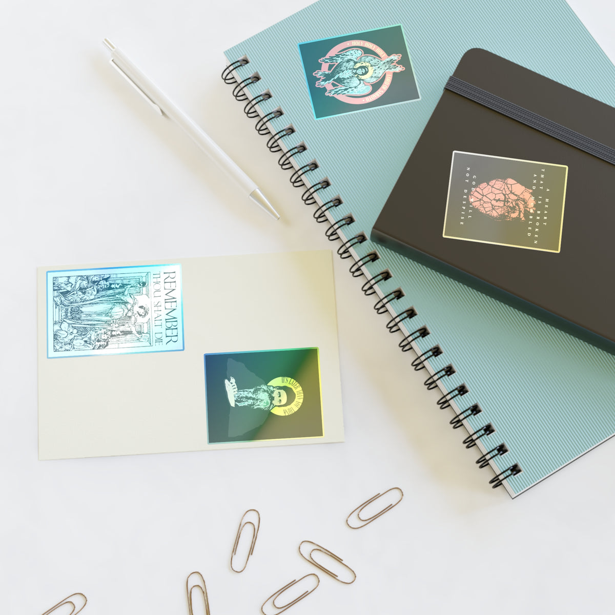 Spiral notebooks, a pen, paper clips, and Bestseller Orthodox Sticker Mix No. 4 on a white surface.