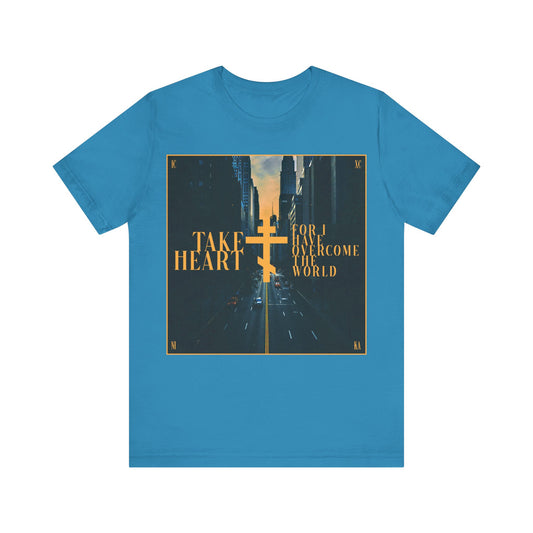 Aqua cotton t-shirt featuring a modern city street scene and “Take Heart, For I Have Overcome the World” (John 16:33). Inspired by Orthodox Christian faith—rejoice in hope and let sorrow turn to joy.