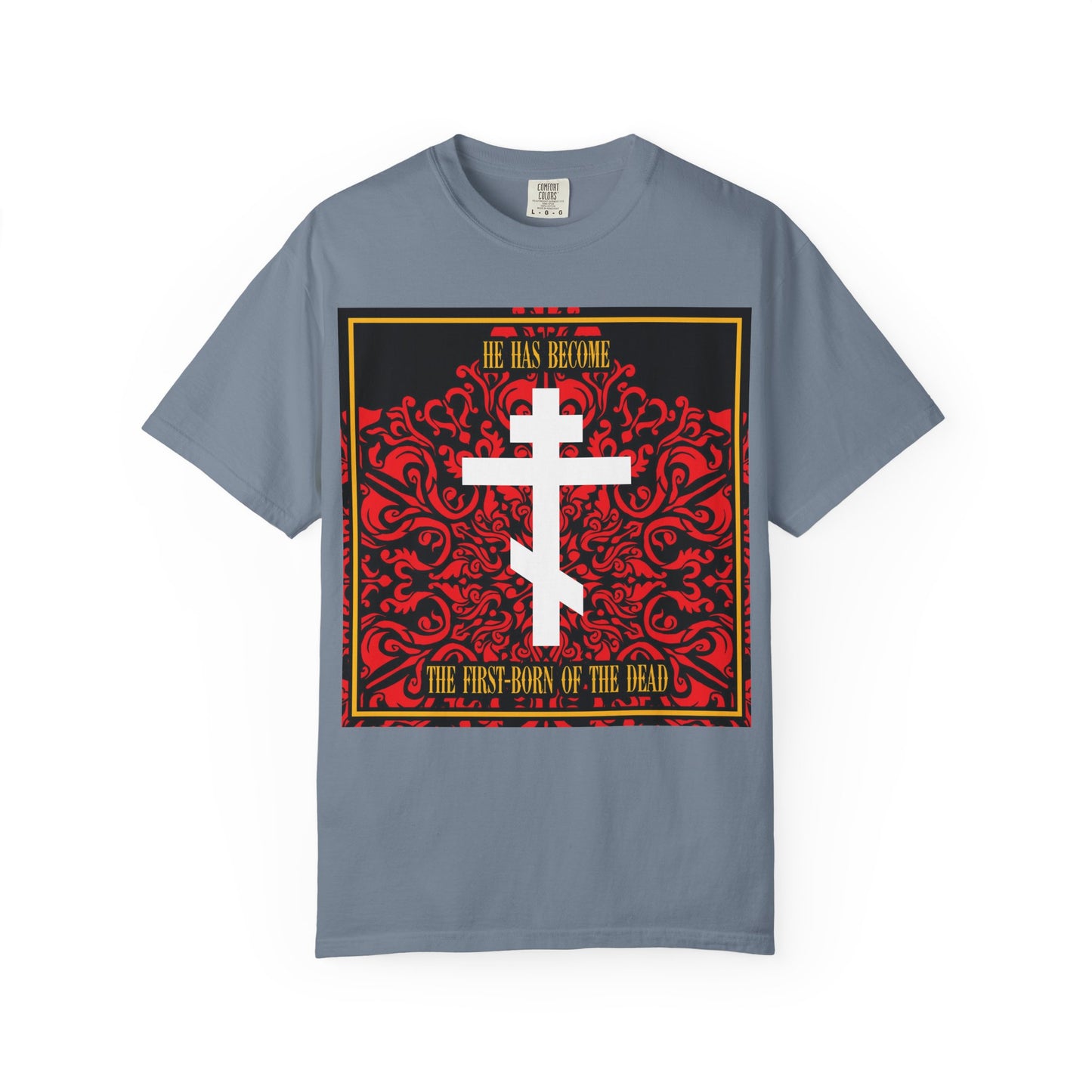 Blue Jean heavyweight cotton unisex tee featuring an ornate red floral texture, a white Orthodox cross, and the bold message: He Has Become the First-Born of the Dead. This Christian shirt is perfect for anyone seeking a meaningful Bible verse design with timeless style.