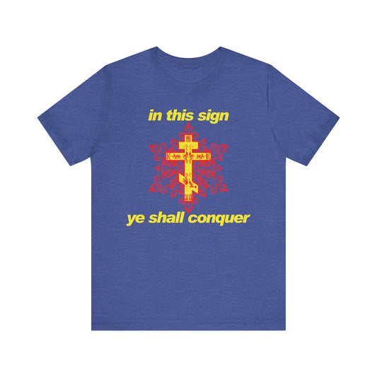 Heather True Royal t-shirt featuring a modern red and yellow design with the phrase "In This Sign Ye Shall Conquer" in bold typography. Inspired by the wisdom of St. Theophan the Recluse, this lightweight cotton unisex tee is a subtle Orthodox Christian reminder to stand firm in faith and prayer against temptation.