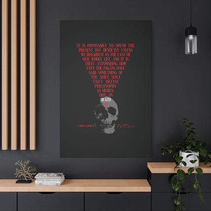 The Present Day As the Last Day of Our Life" Orthodox canvas wall art, featuring a skull with a red cross, hangs above a modern black and wood cabinet with plants on a gray wall.