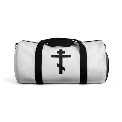 White duffel bag with black handles featuring a black Orthodox cross and the phrase "May I never boast, except in the cross of our Lord Jesus Christ" (Gal 6:14). Perfect for Orthodox Christians, inspired by St John Chrysostom's hymn tradition.