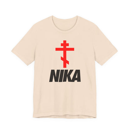 Soft cream t-shirt with a red Eastern Orthodox cross above bold black “NIKA” text, inspired by Christian iconography and minimalist athletic ascetic fashion. Features a NIKE logo mashup and “Jesus Christ Conquers” theme.
