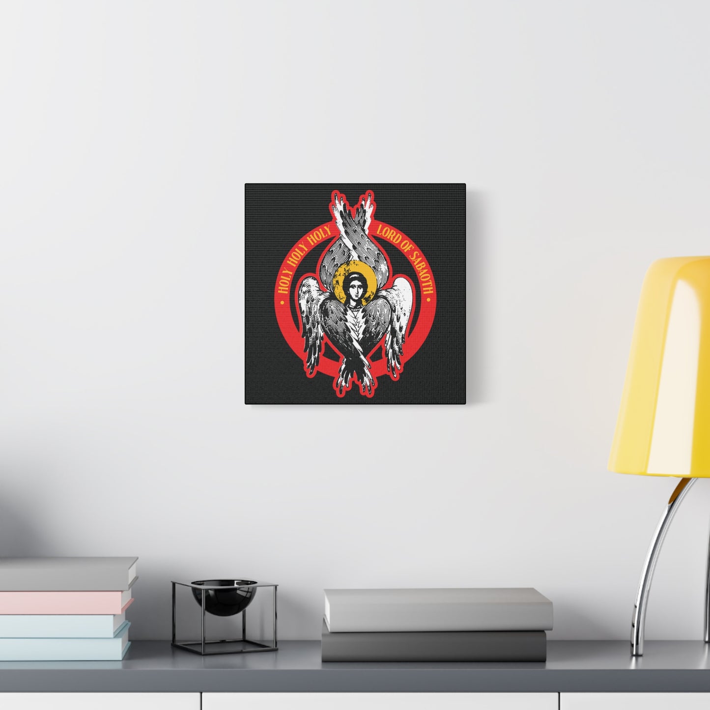 The "Holy Holy Holy, Lord of Sabaoth | Isaiah 6 | Orthodox Seraphim Angel IconoGraphic" Christian wall art hangs on a white wall above a gray cabinet with books and a yellow lamp.