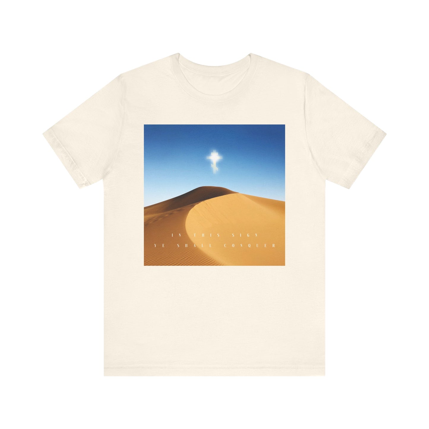Natural cotton unisex tee with a desert sun scene, blue sky, and text: In This Sign Ye Shall Conquer—echoing the Cross and the spirit of Orthodox Christianity.