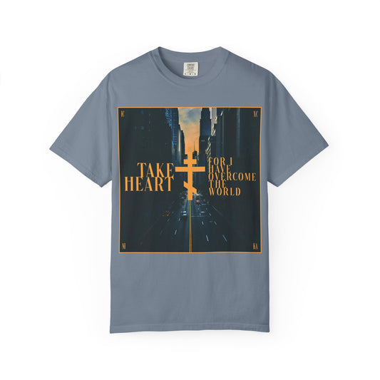 Blue Jean heavyweight cotton unisex tee featuring a modern city street scene with a yellow Orthodox cross and the text: “Take heart, for I have overcome the world” (John 16:33)—a reminder that believers are promised joy in place of sorrow.