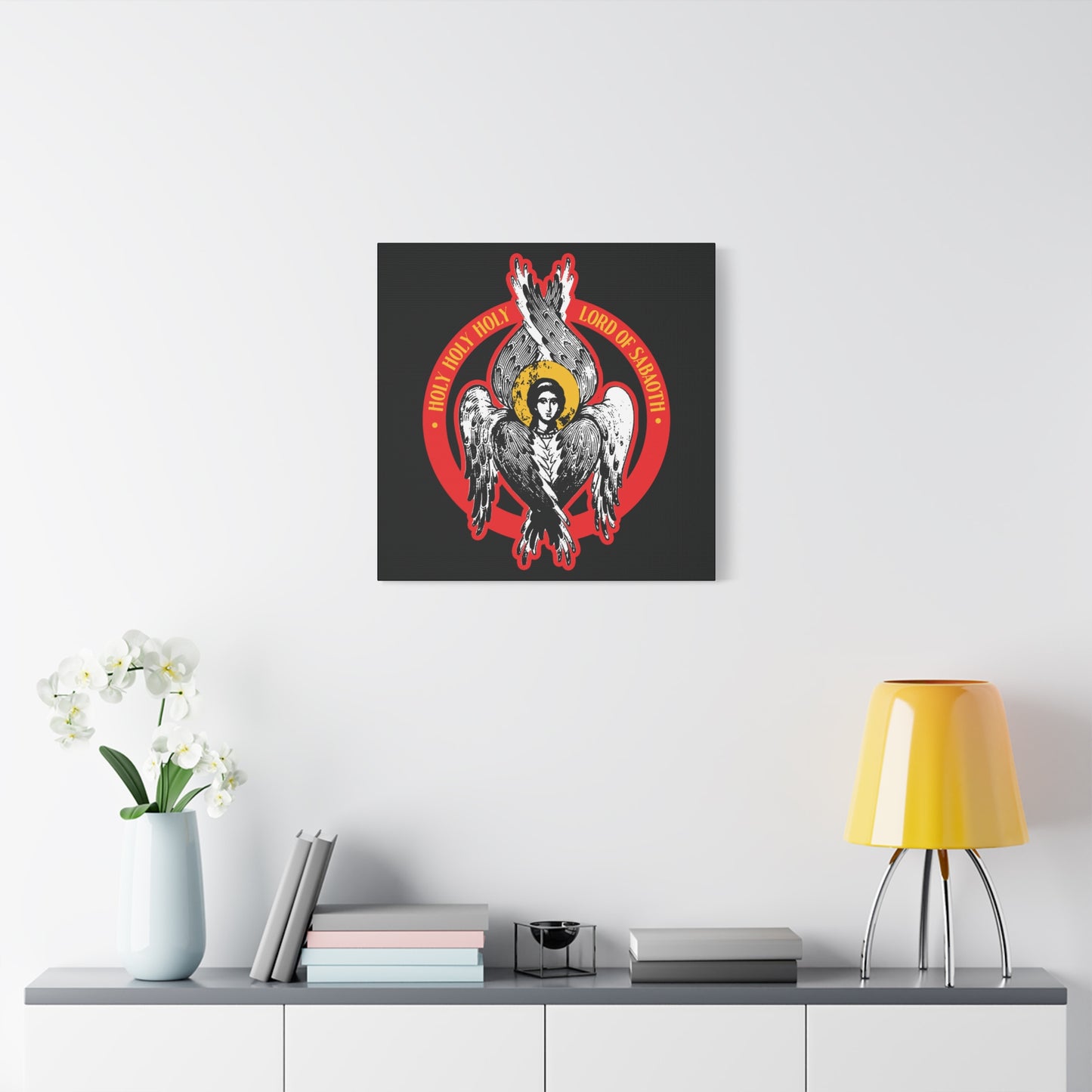The "Holy Holy Holy, Lord of Sabaoth" Orthodox Seraphim Angel IconoGraphic—Christian wall art inspired by Isaiah 6—adorns a white wall above a shelf with books, a lamp, and flowers for a serene, sacred touch.