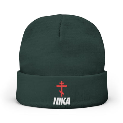 Dark green knit beanie with an embroidered red Orthodox cross and the word NIKA in white, blending Orthodox Christian motifs with an athletic aesthetic. Product: NIKA Red Embroidered Orthodox Cross | NIKE Logo Mashup Beanie.
