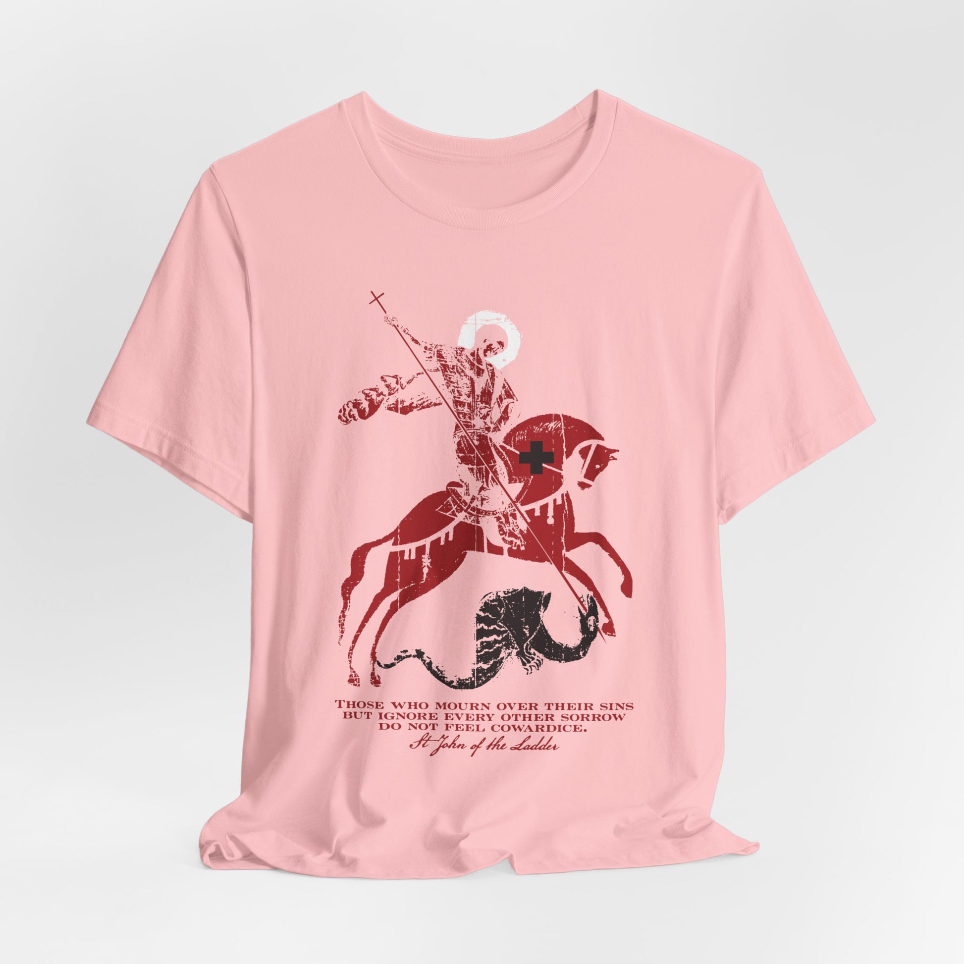 A pink unisex lightweight cotton t-shirt featuring a graphic of St George slaying the dragon, with black cursive text below inspired by St John Climacus’s teachings on mourning over one’s sins.